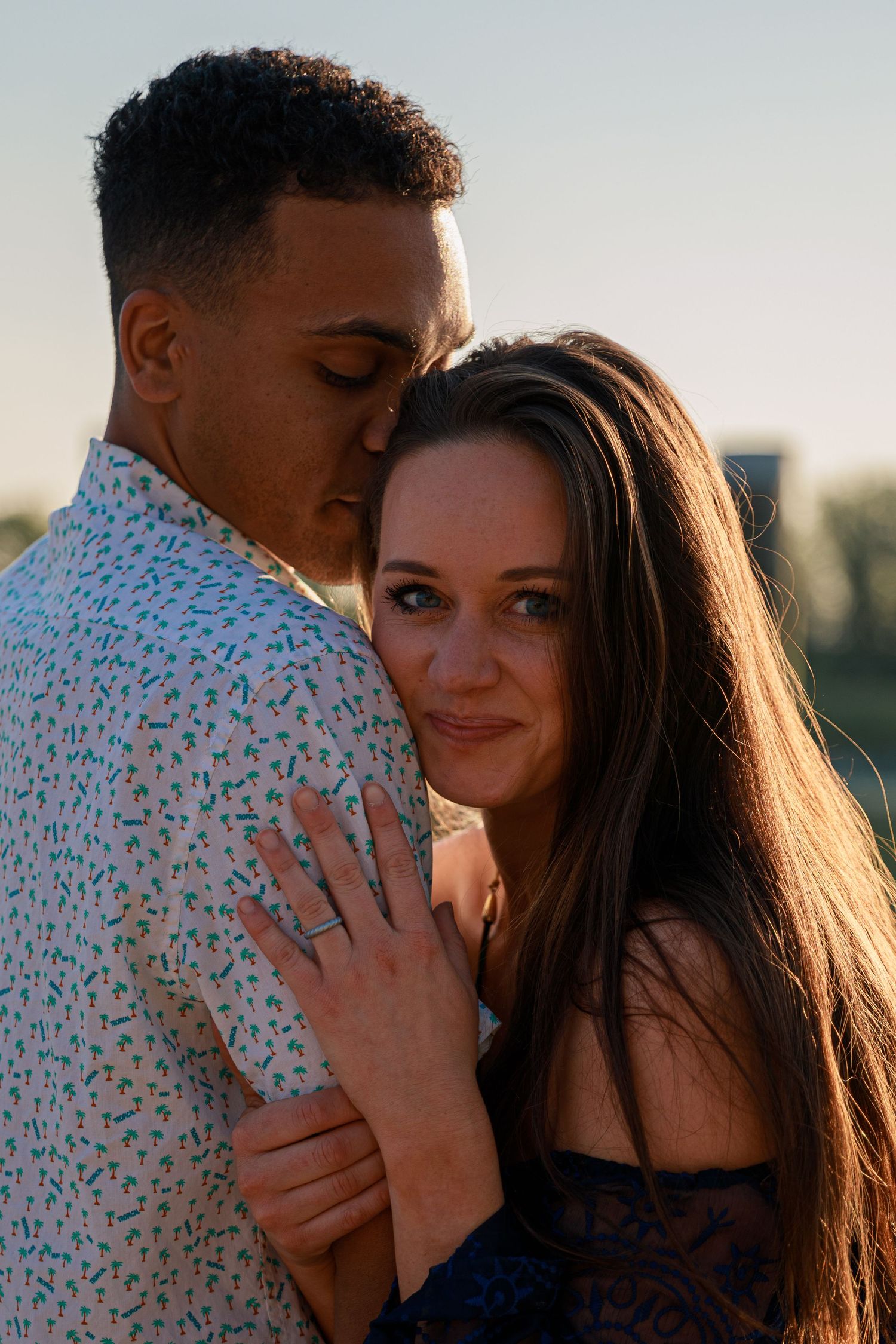 Couple sharing tender moment outdoors during golden hour photoshoot.