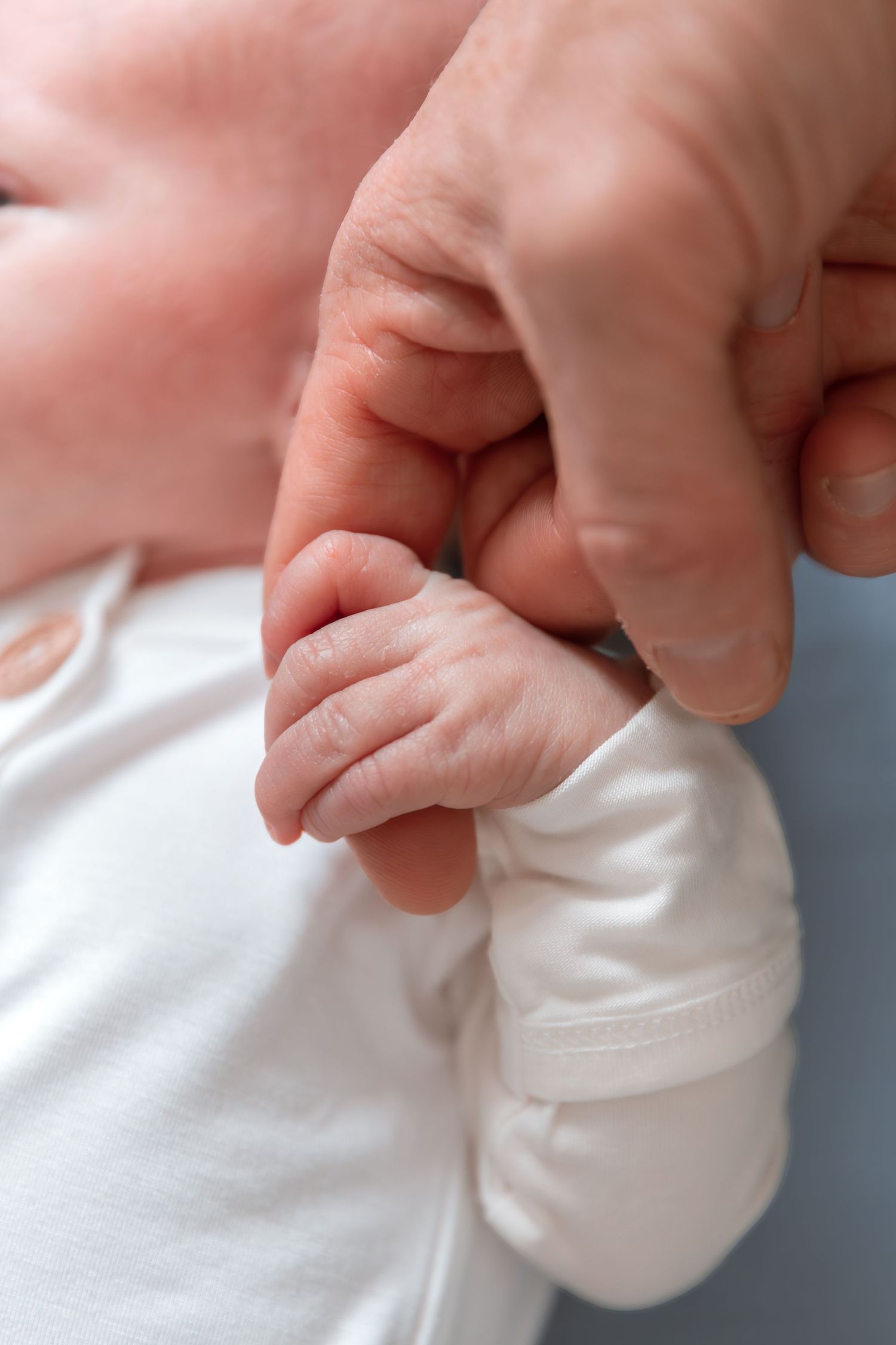 Close-up detail shot of tiny white baby shoes against light background.