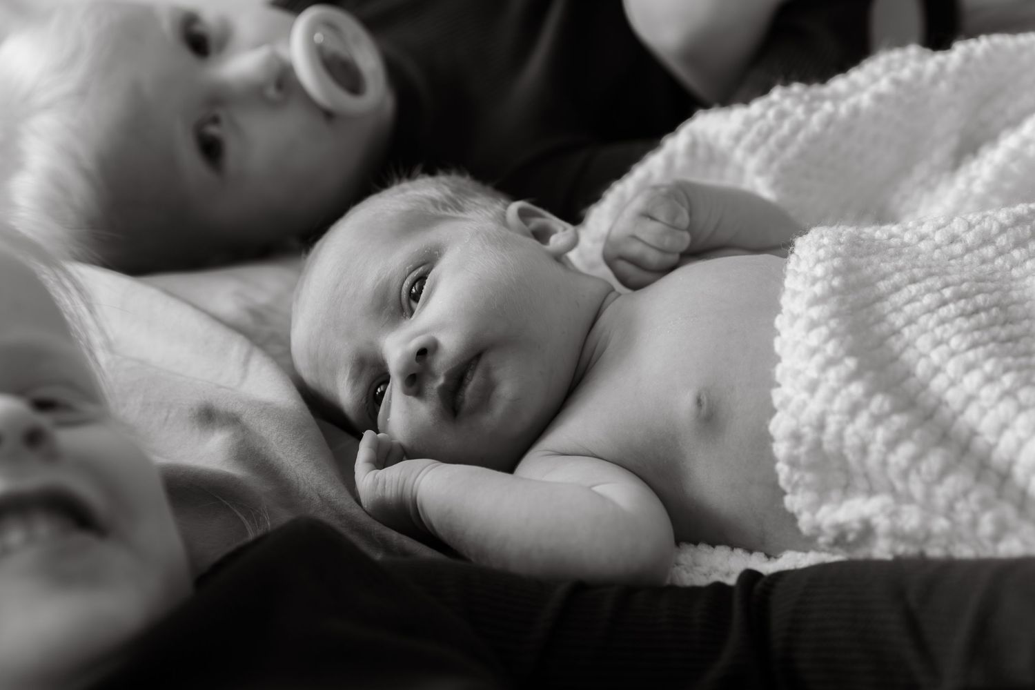 Black and white portrait of sleeping infant on textured blanket.