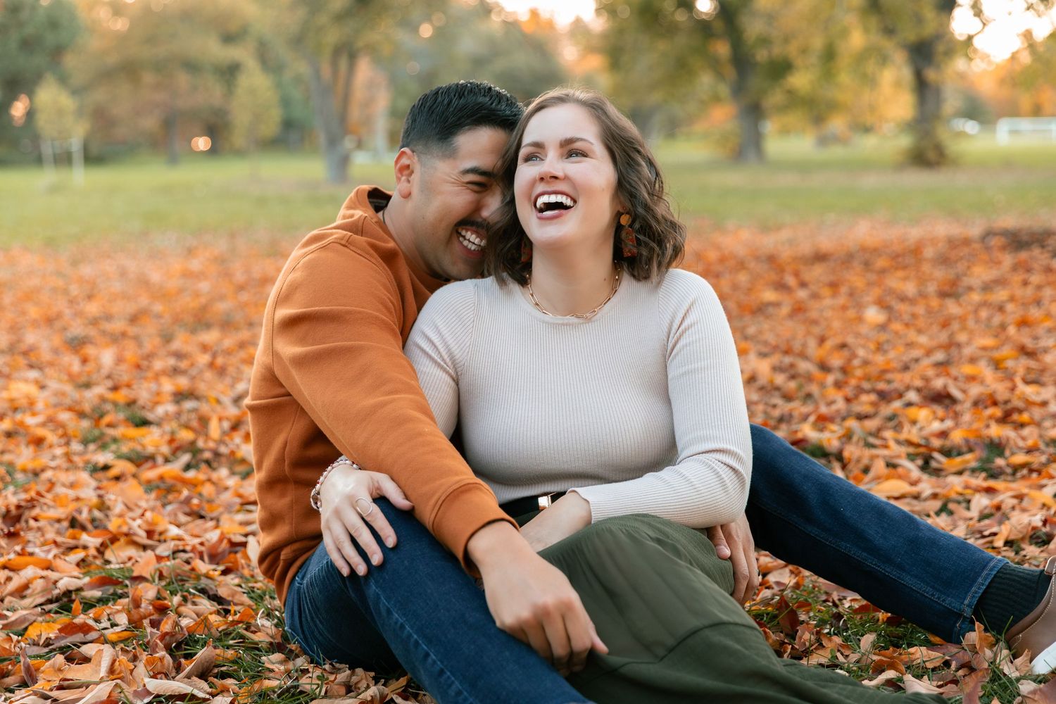 Casual outdoor couple's portrait session among fallen autumn leaves.