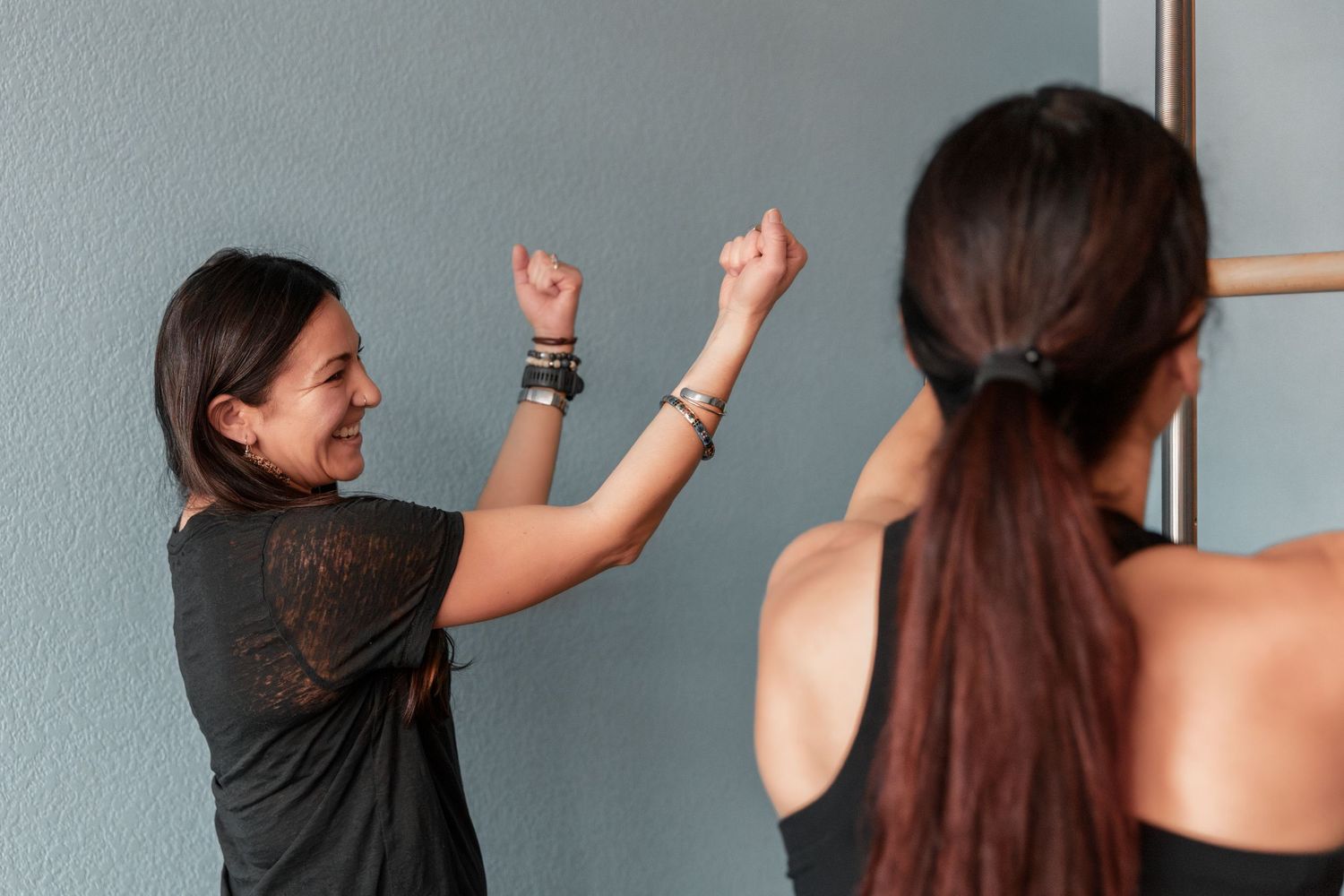 Person demonstrating dynamic stretching poses against blue wall.