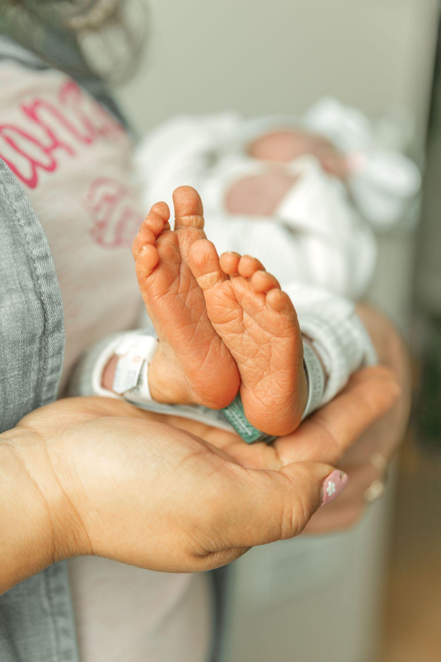 Close-up of a newborn baby's tiny feet resting gently in an adult's cupped hands.