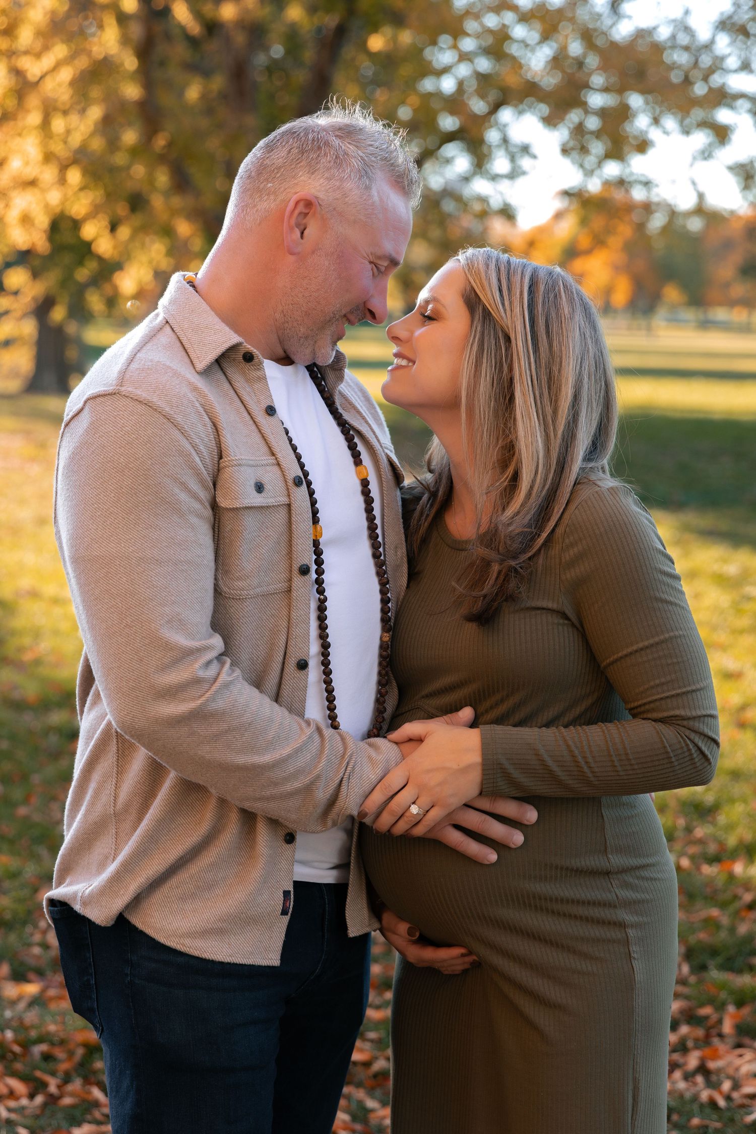 Intimate moment between couple in autumn park setting with warm lighting.