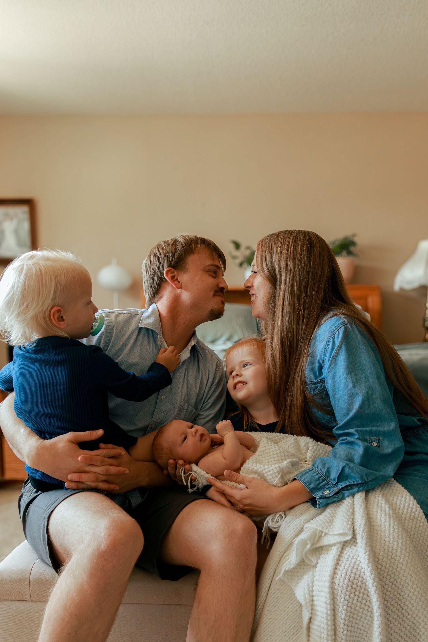 Family lying together on couch sharing intimate moments.