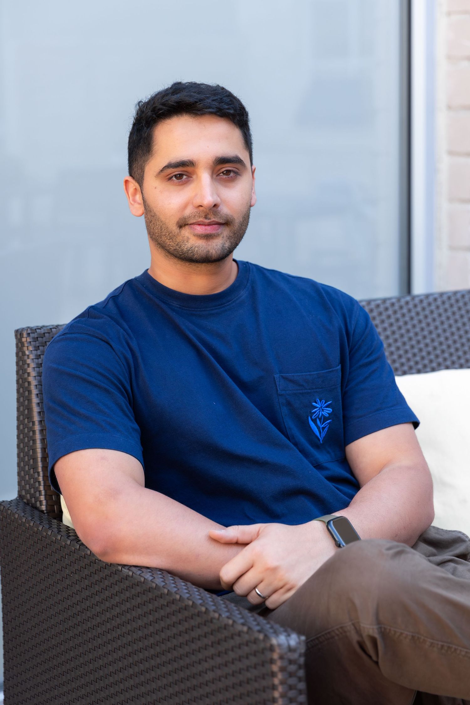 Person in a navy blue t-shirt sitting relaxed on outdoor patio furniture.