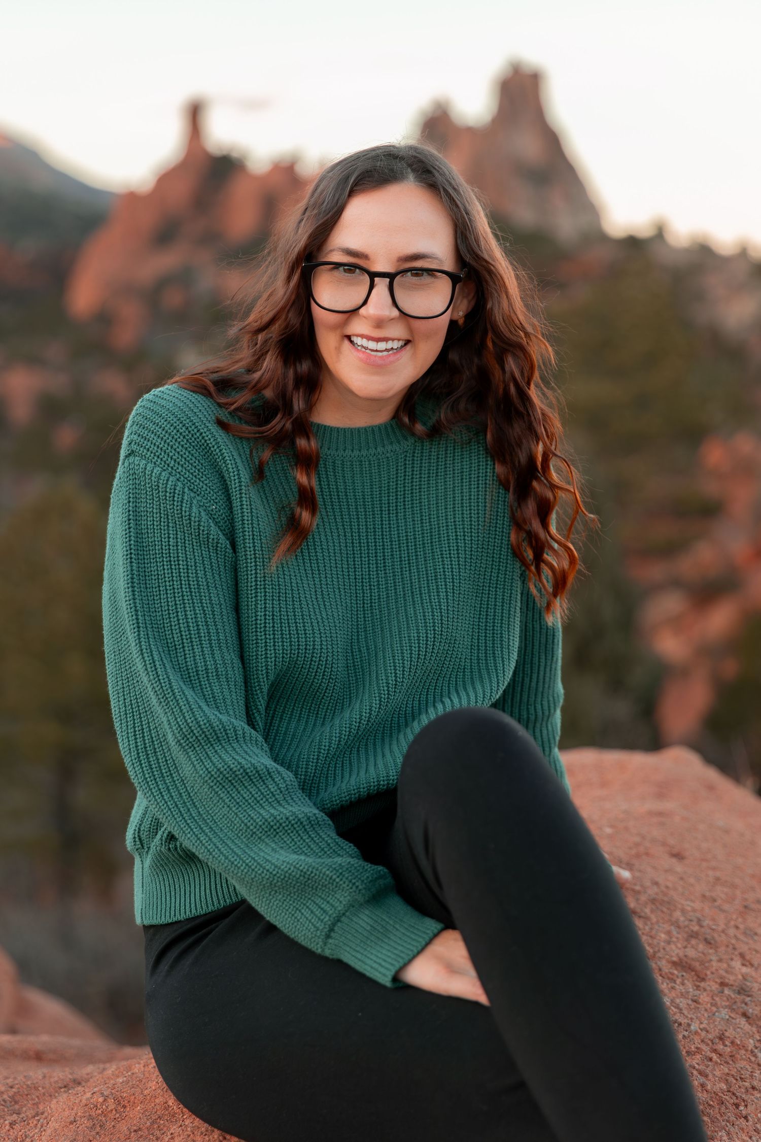 Portrait series of someone in a green sweater sitting on rocks at sunset.