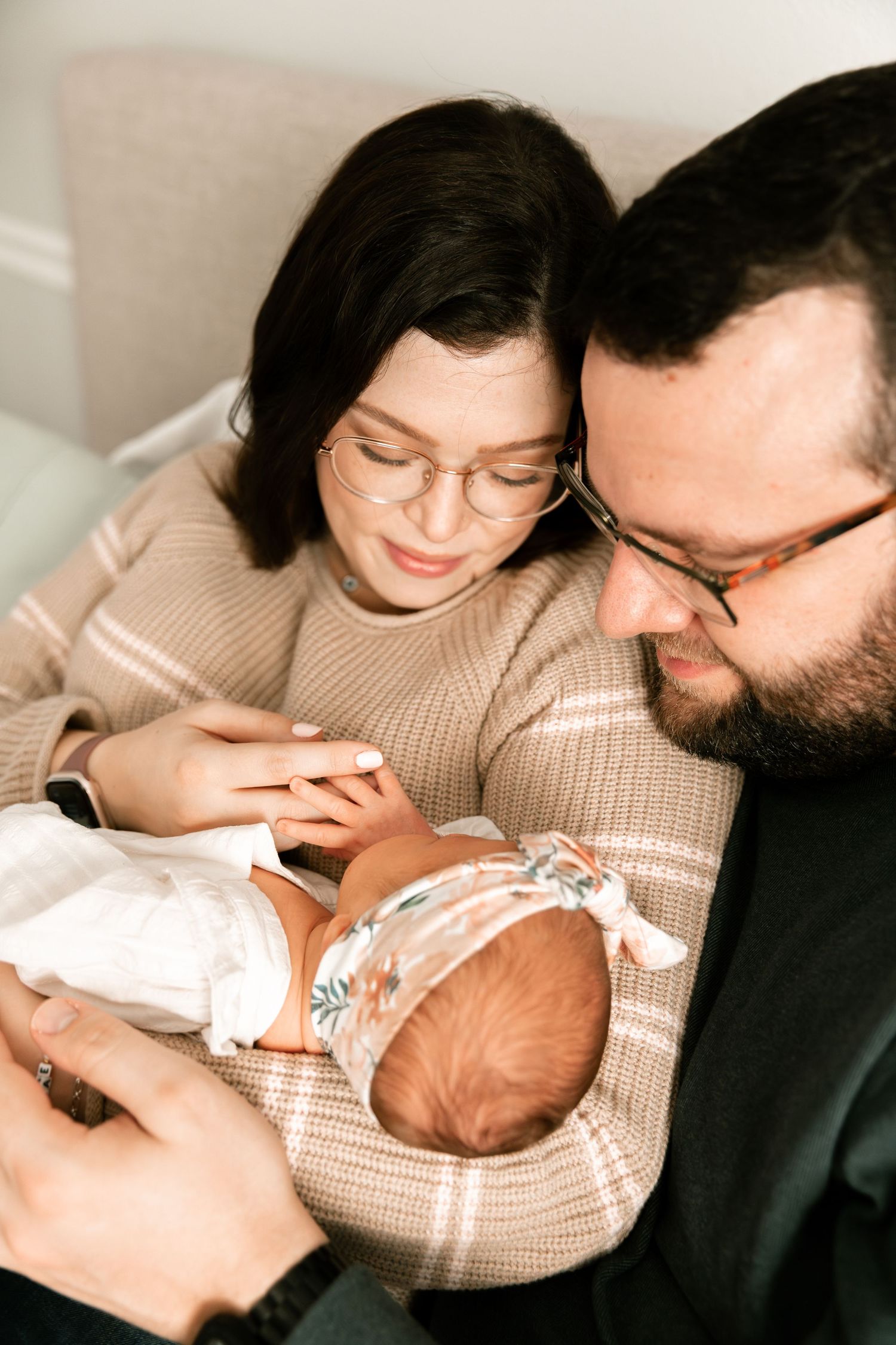 A family shares tender moments with their newborn baby in a series of warm, intimate photographs.