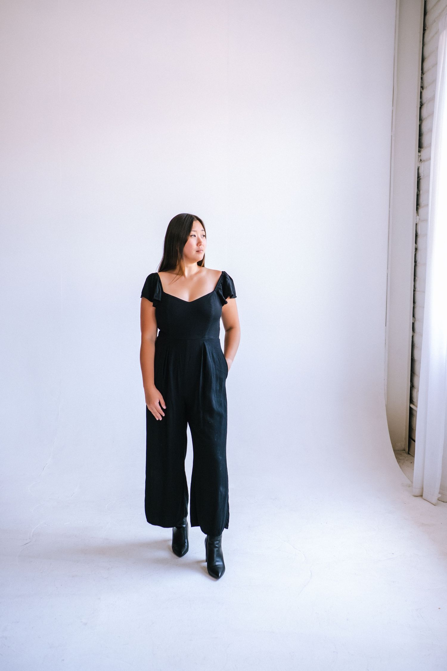 Person in black dress poses against white studio backdrop in artistic photo sequence.