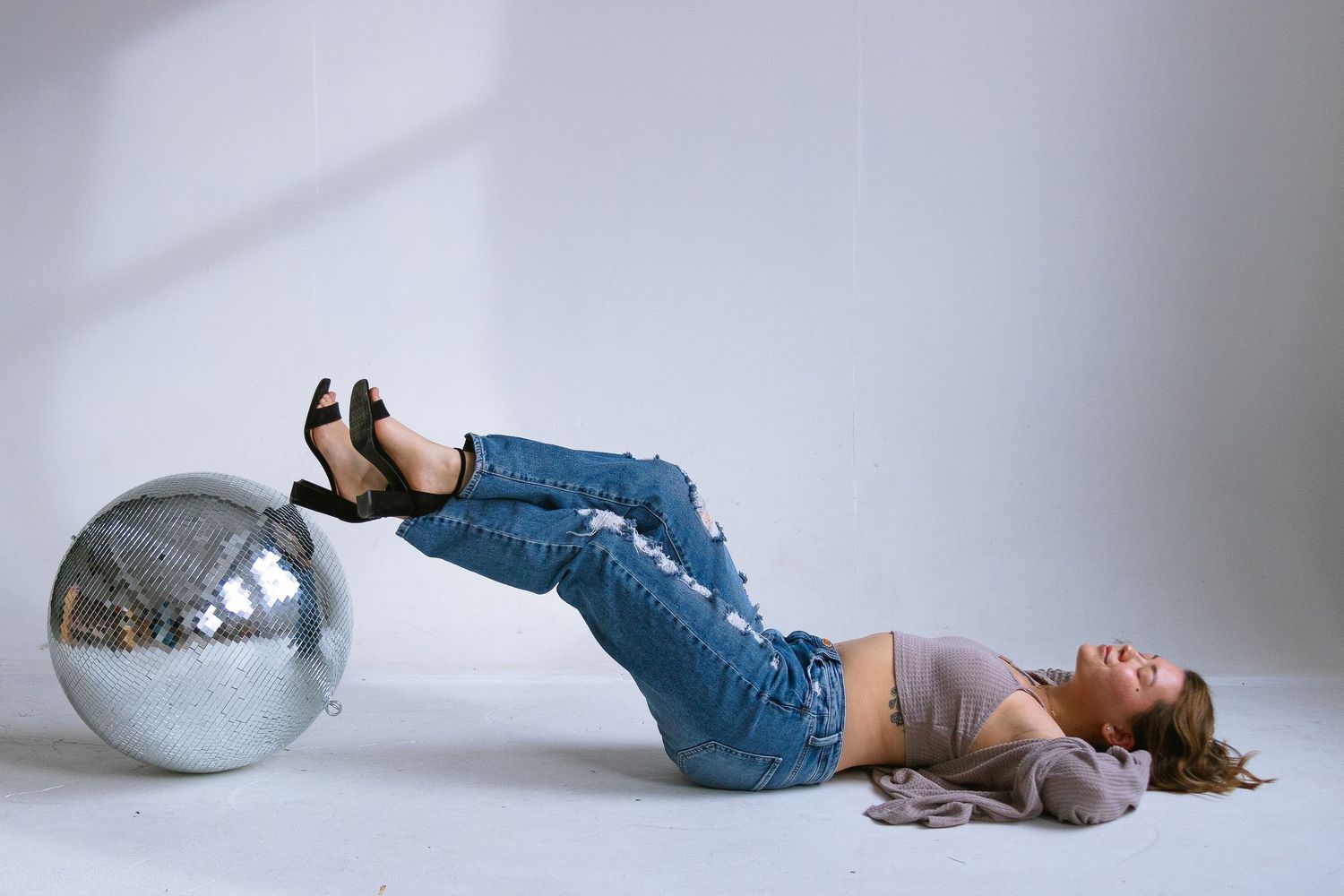 Artistic studio portrait with silver disco ball and casual fashion styling.