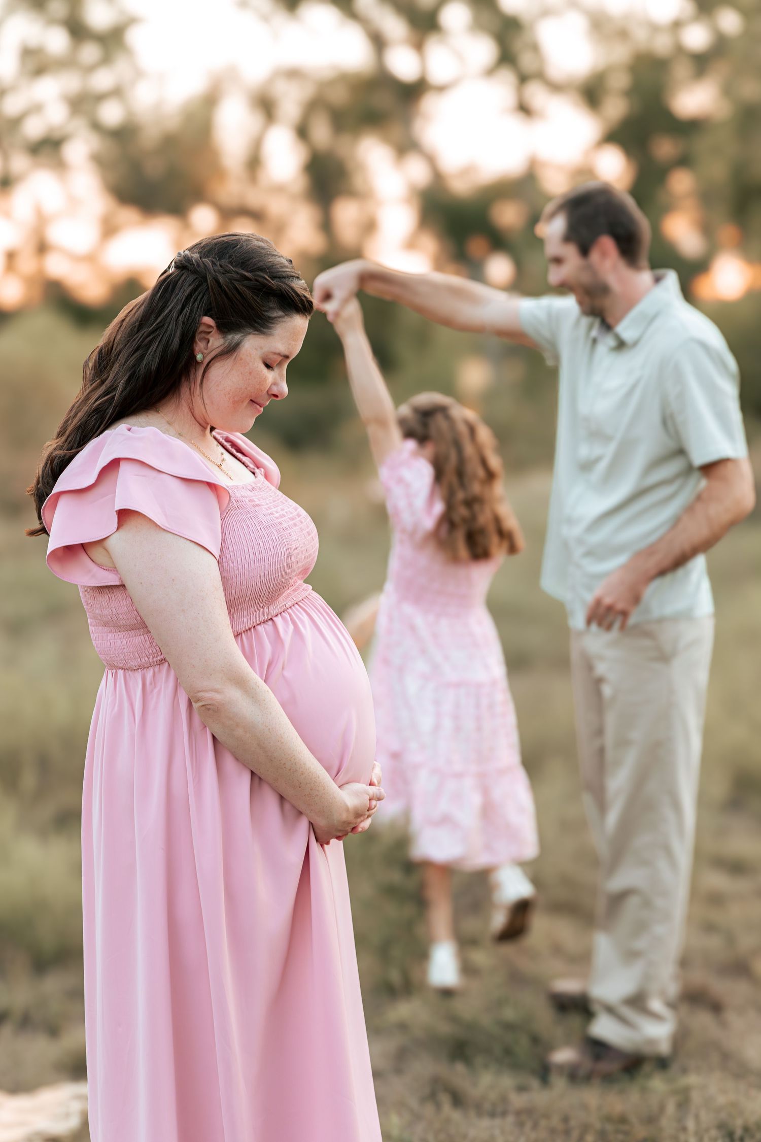 A family moment captured at sunset with figures in pink and white clothing.