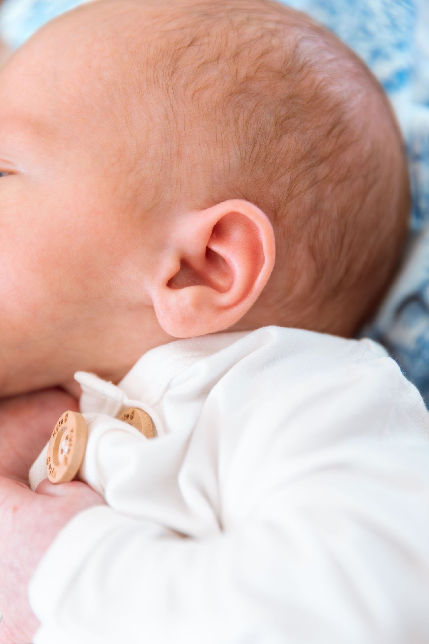 Close-up view of a sleeping baby in white clothing against light blue bedding.
