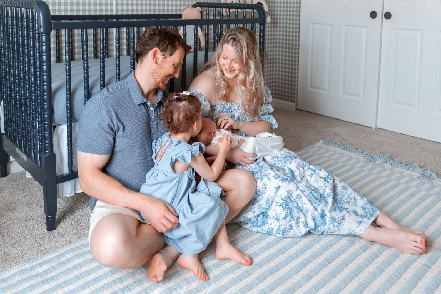 Family lifestyle session on nursery floor with black crib in background.