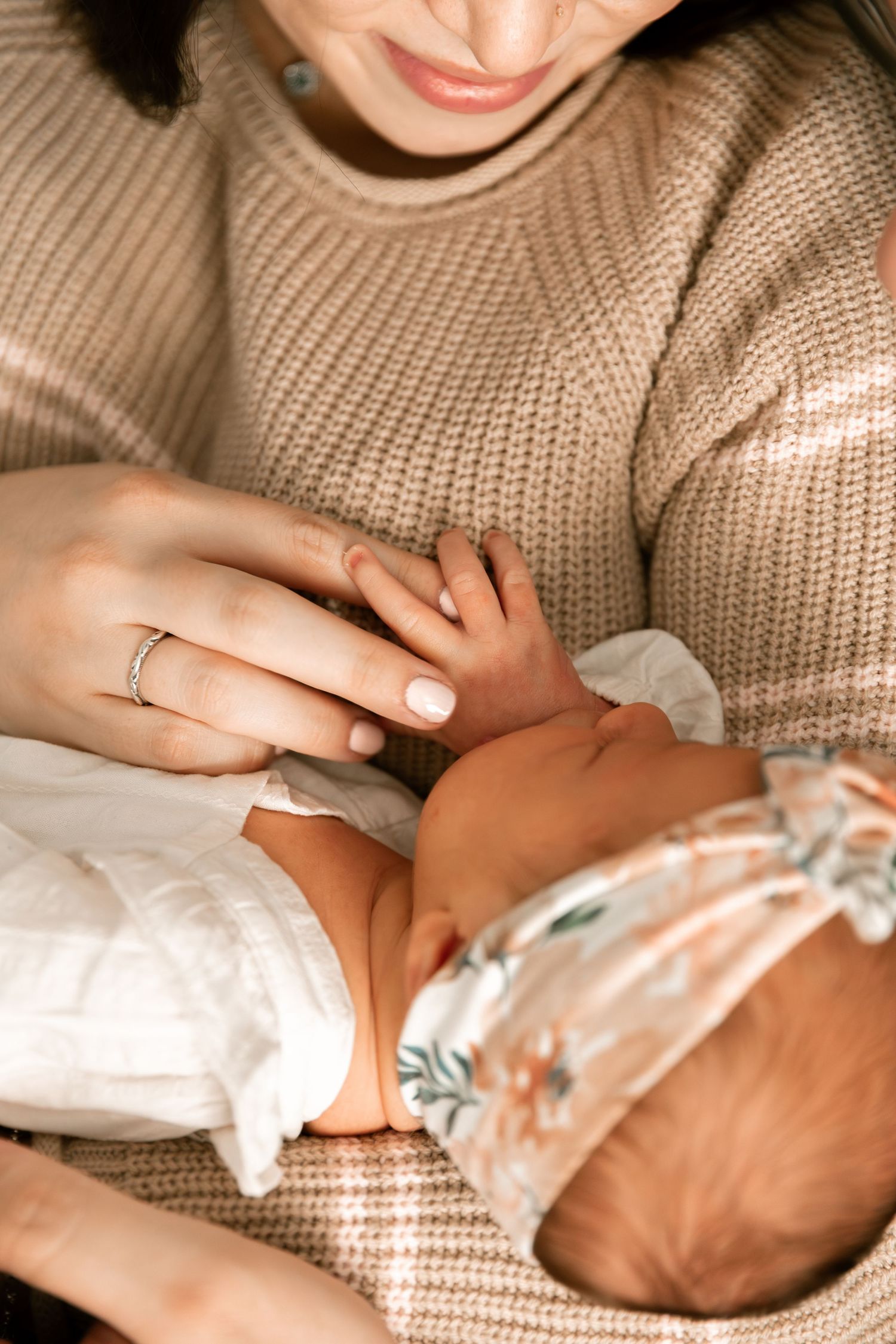 Close-up of hands wearing a cozy beige sweater with a delicate ring on the finger.