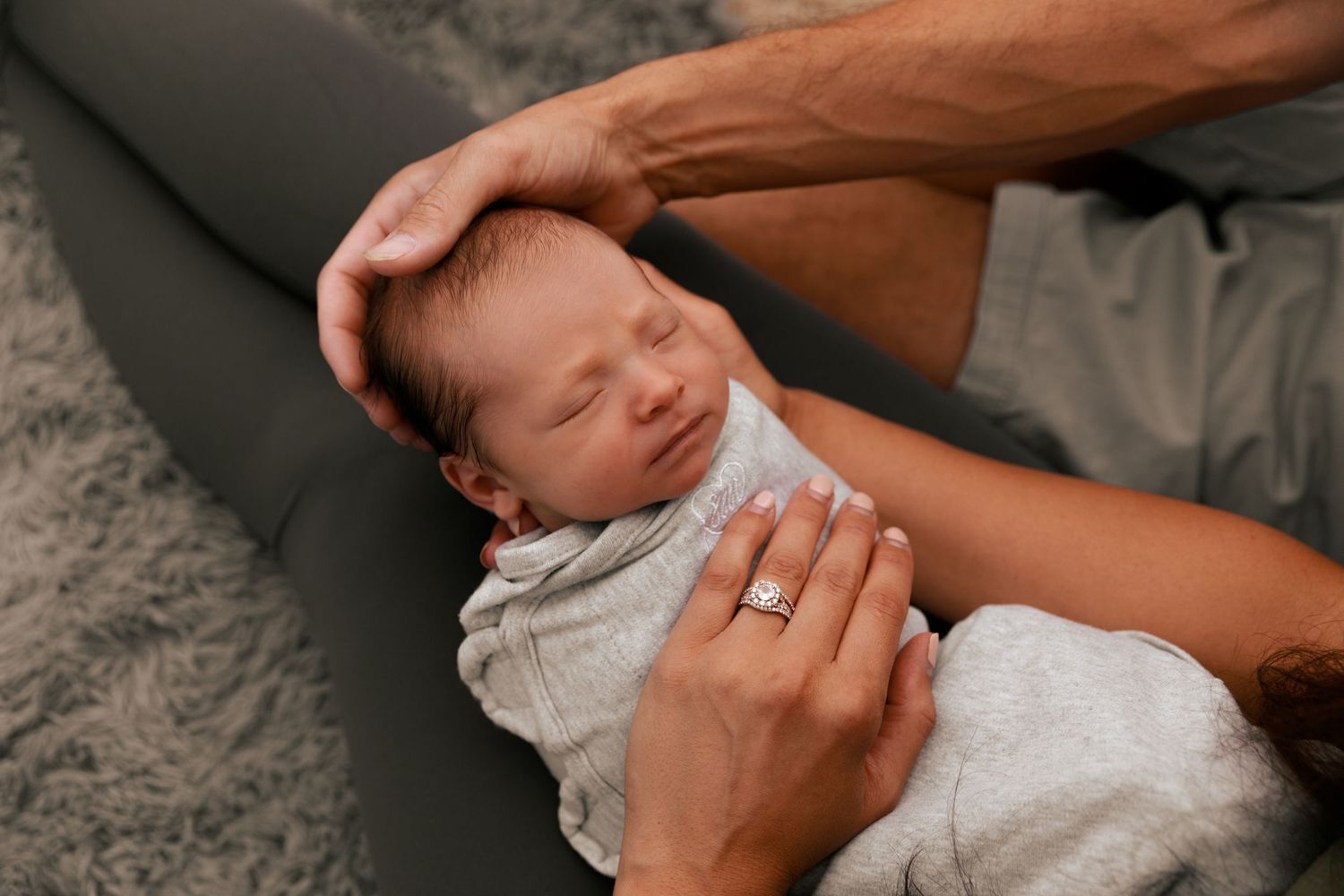 Intimate newborn photography showing gentle hands holding sleeping baby.