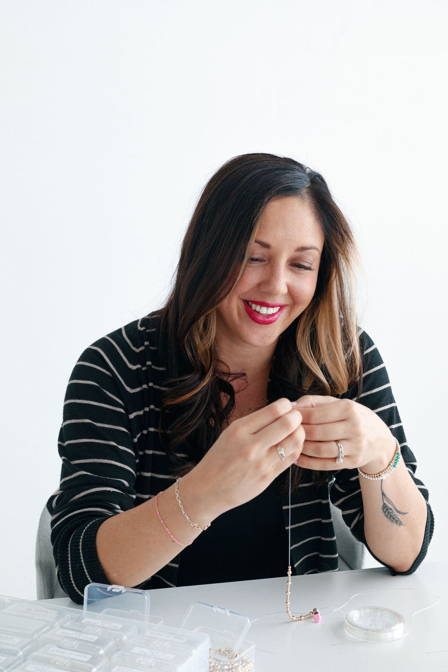 Woman in striped black top working with small objects on white table.