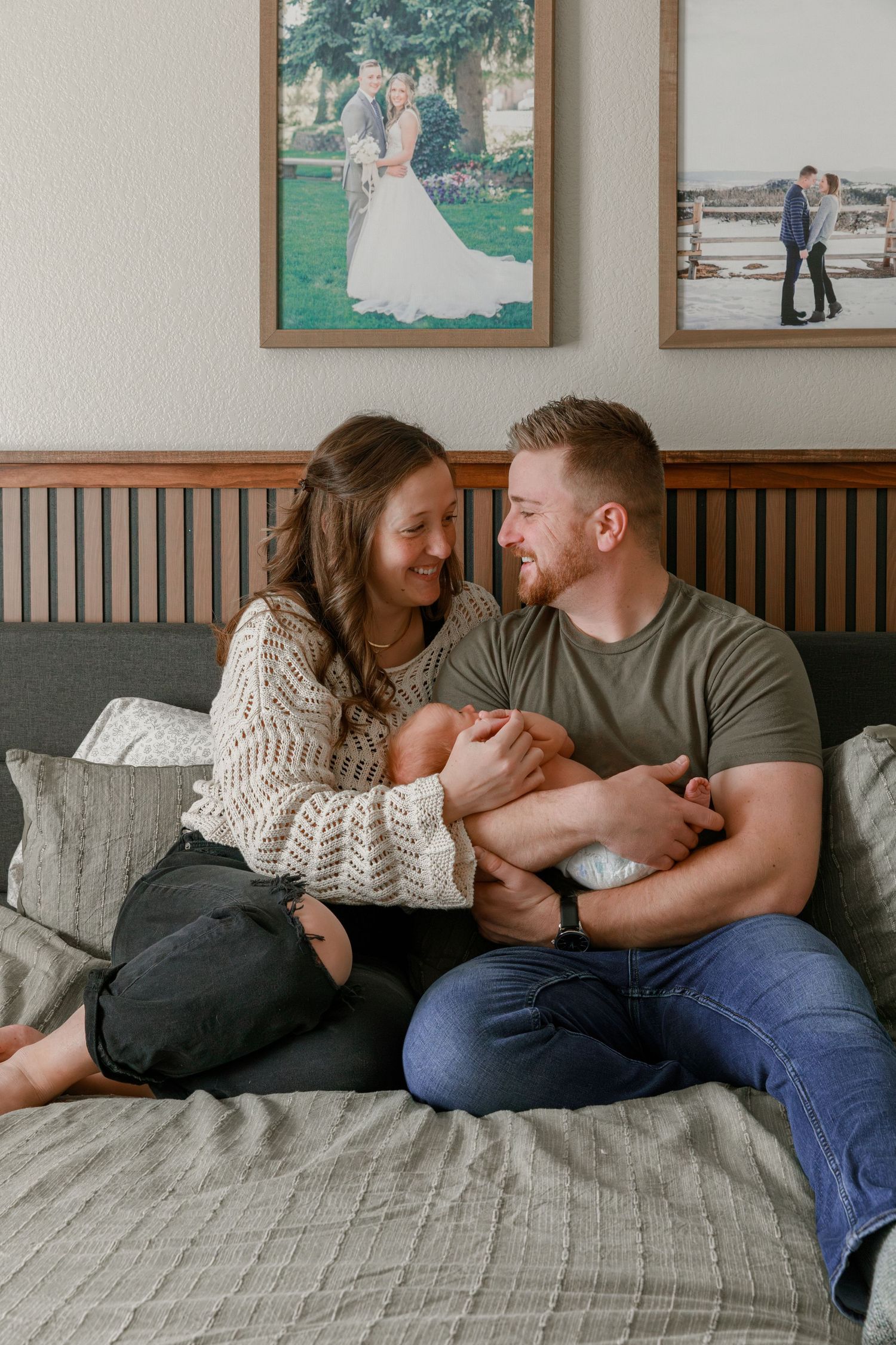 Couple sharing an intimate moment on a bed with framed photos displayed on the wall.