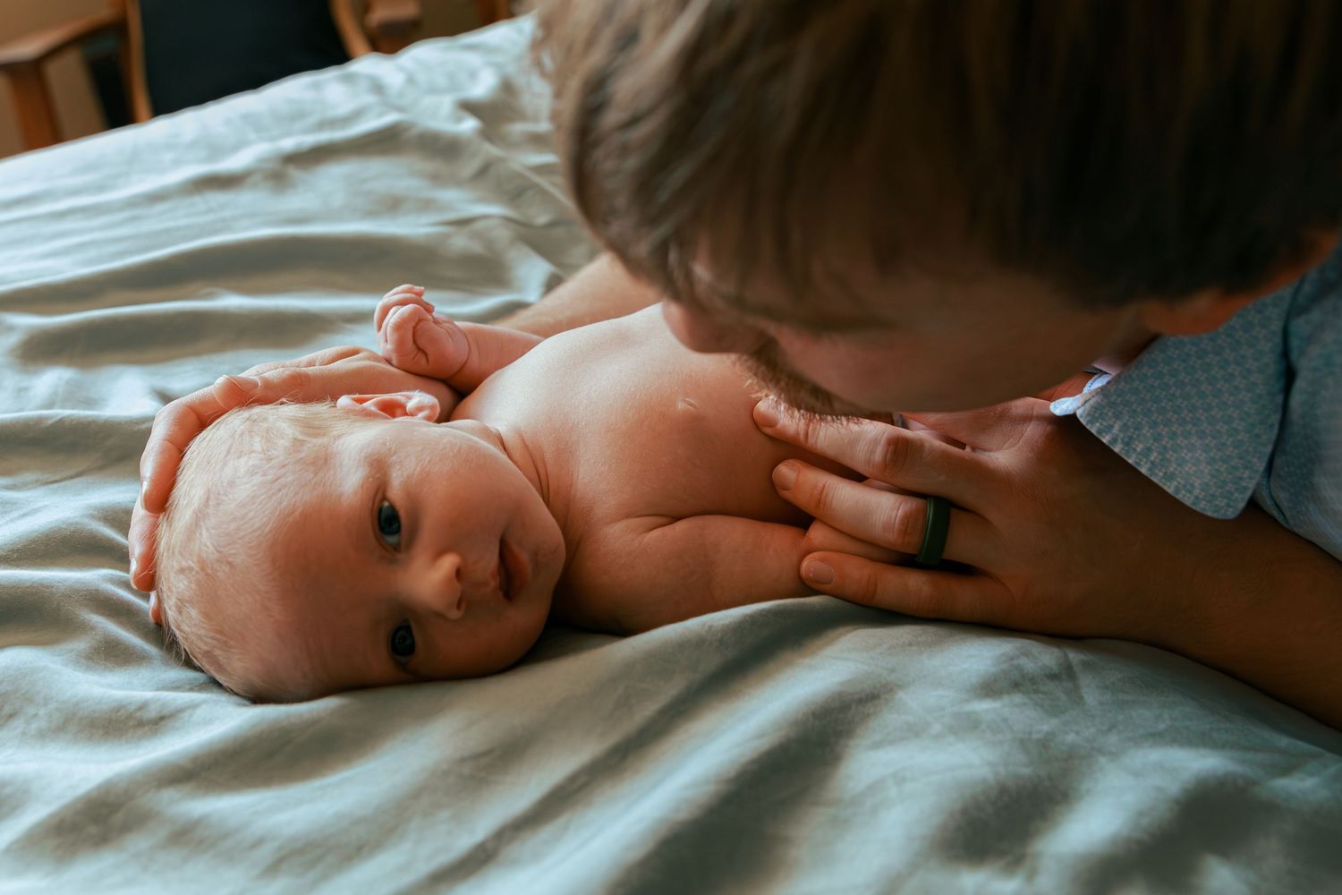 Close-up portrait series of a newborn baby lying on white bedding.