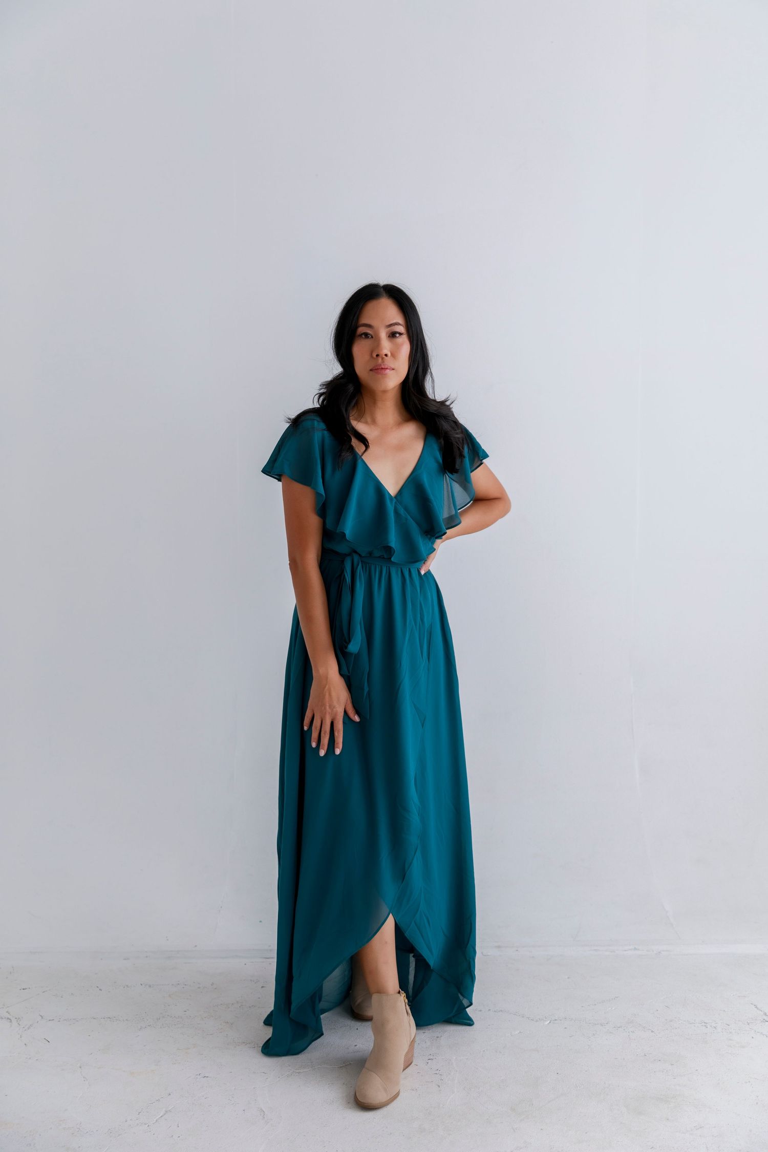 Teal flutter sleeve maxi dress with wrap style bodice and asymmetrical hemline.