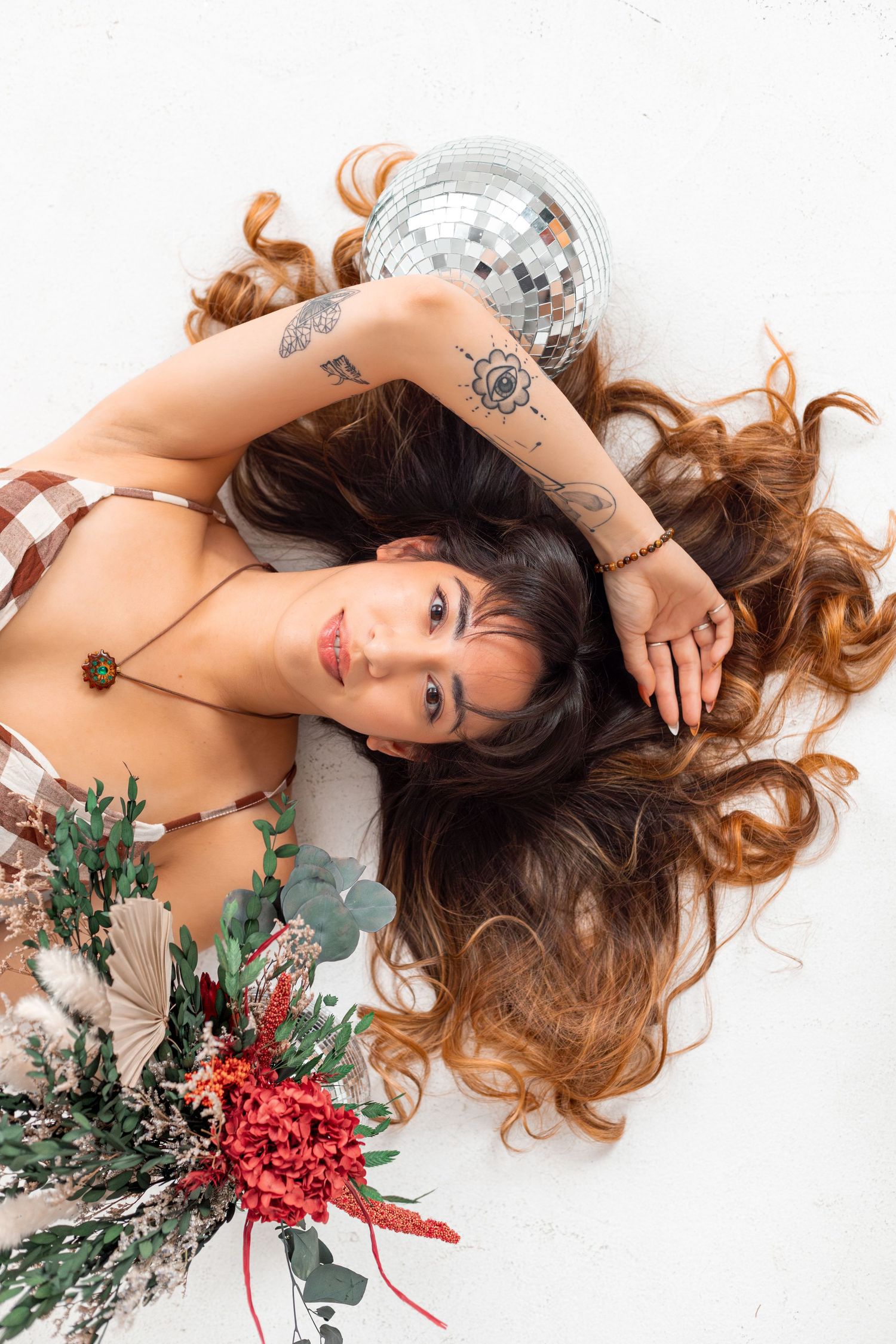 Boudoir photo with disco ball and floral bouquet on white background.