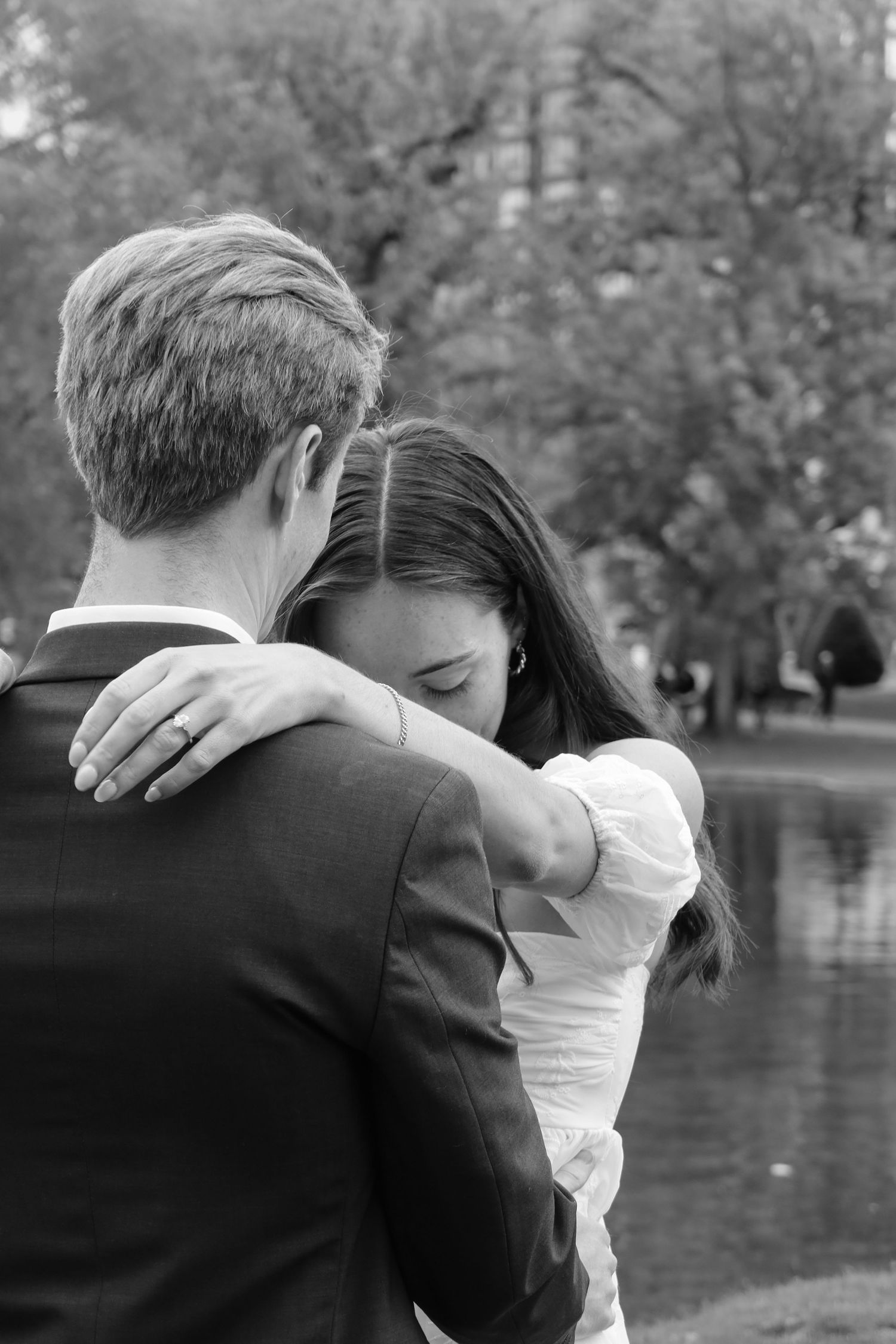 Black and white photo of an intimate embrace near a lake.