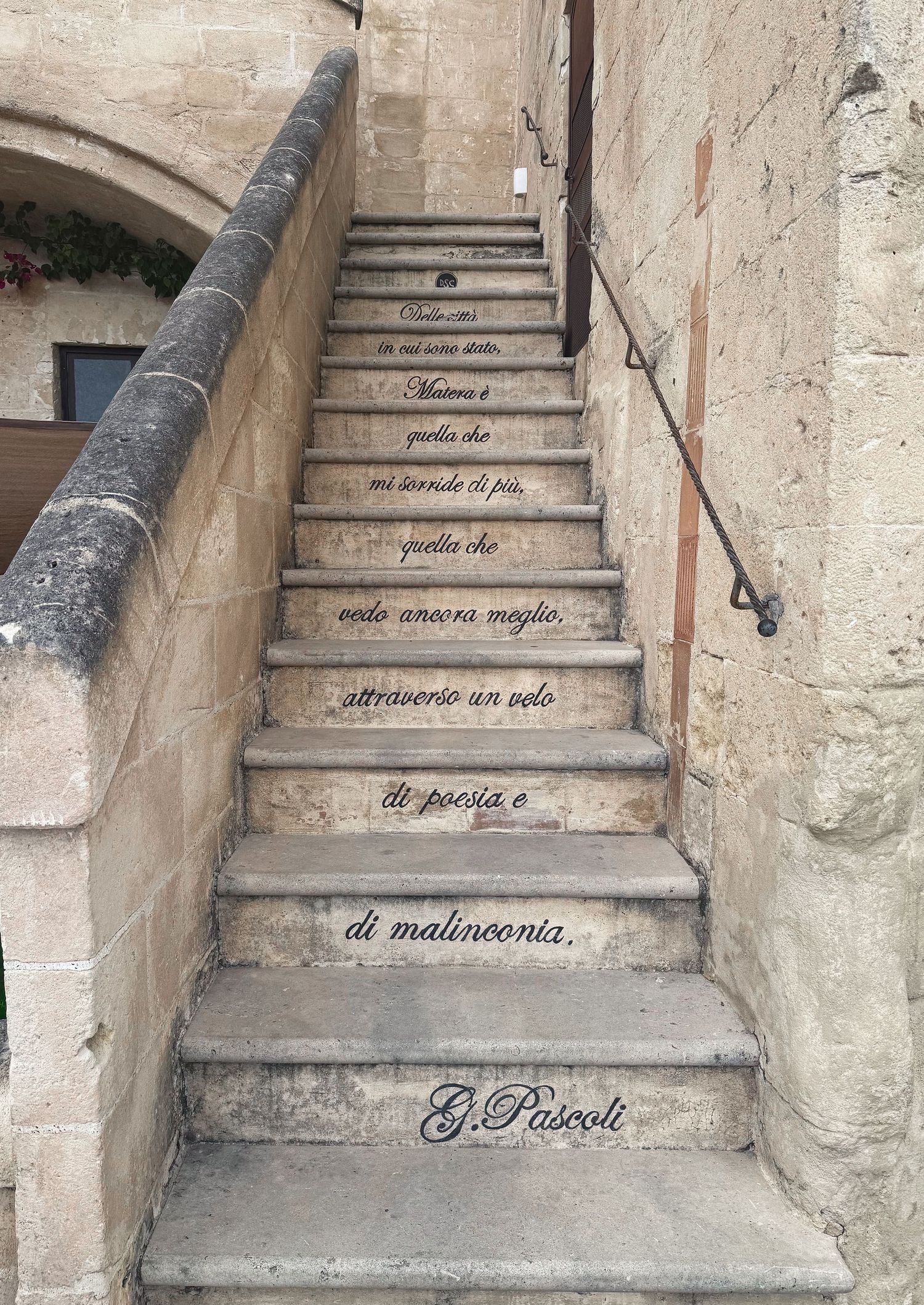 Stone steps with Italian text written on each riser leading upwards in an old building.