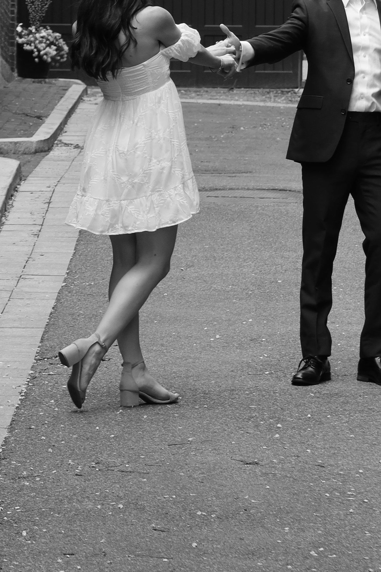Close-up of dancing feet and formal attire on a cobblestone street.