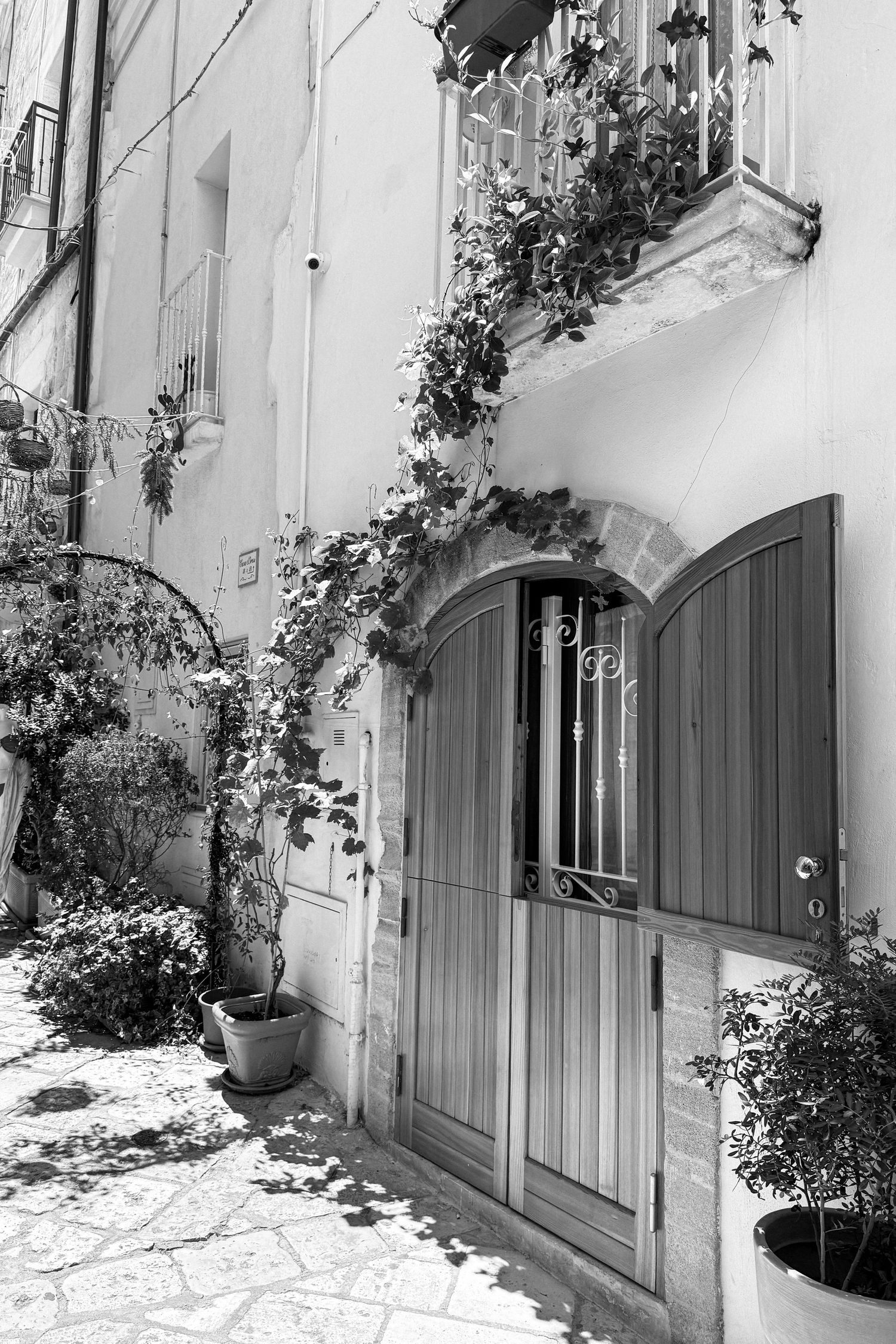 Rustic white stone walls with arched doorways and climbing plants create a charming Mediterranean atmosphere.