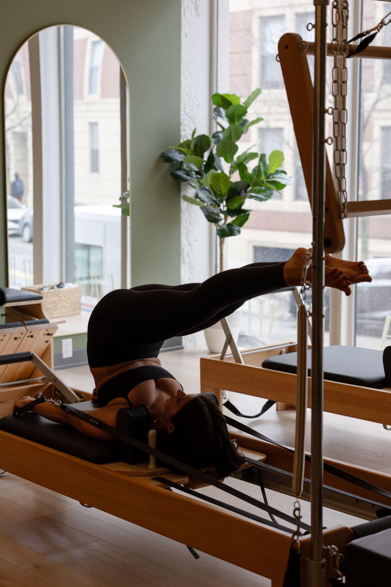 Pilates reformer machine setup in a bright studio with wooden floors and natural lighting.