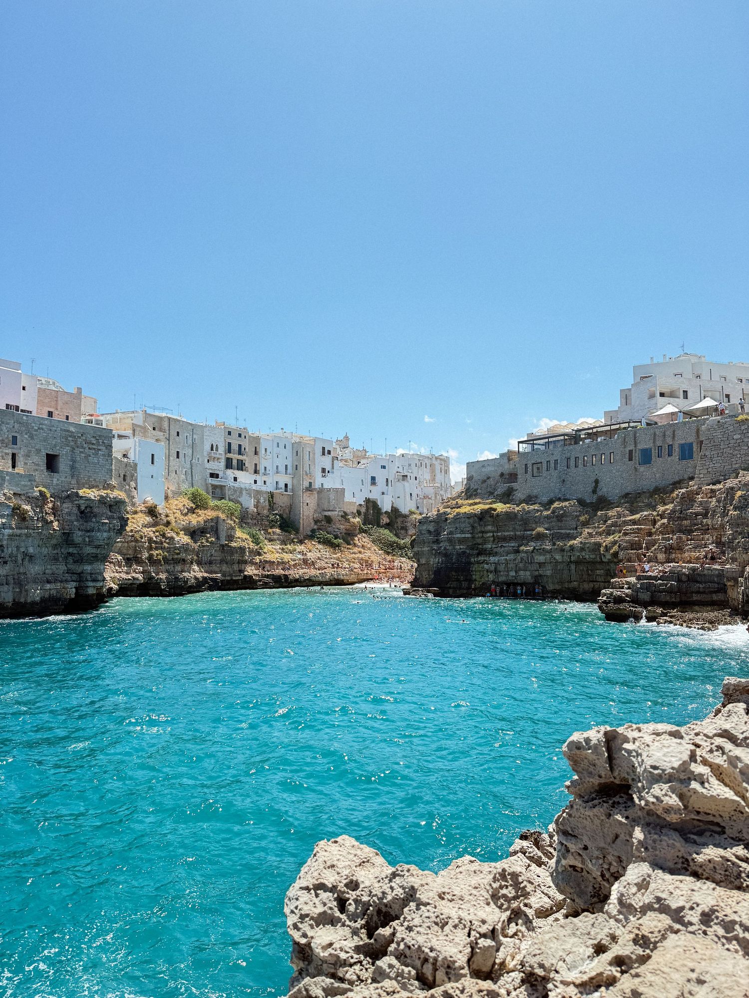 Stunning turquoise Mediterranean waters meet white buildings along rocky cliffs in the coastal town of Polignano a Mare, Italy.