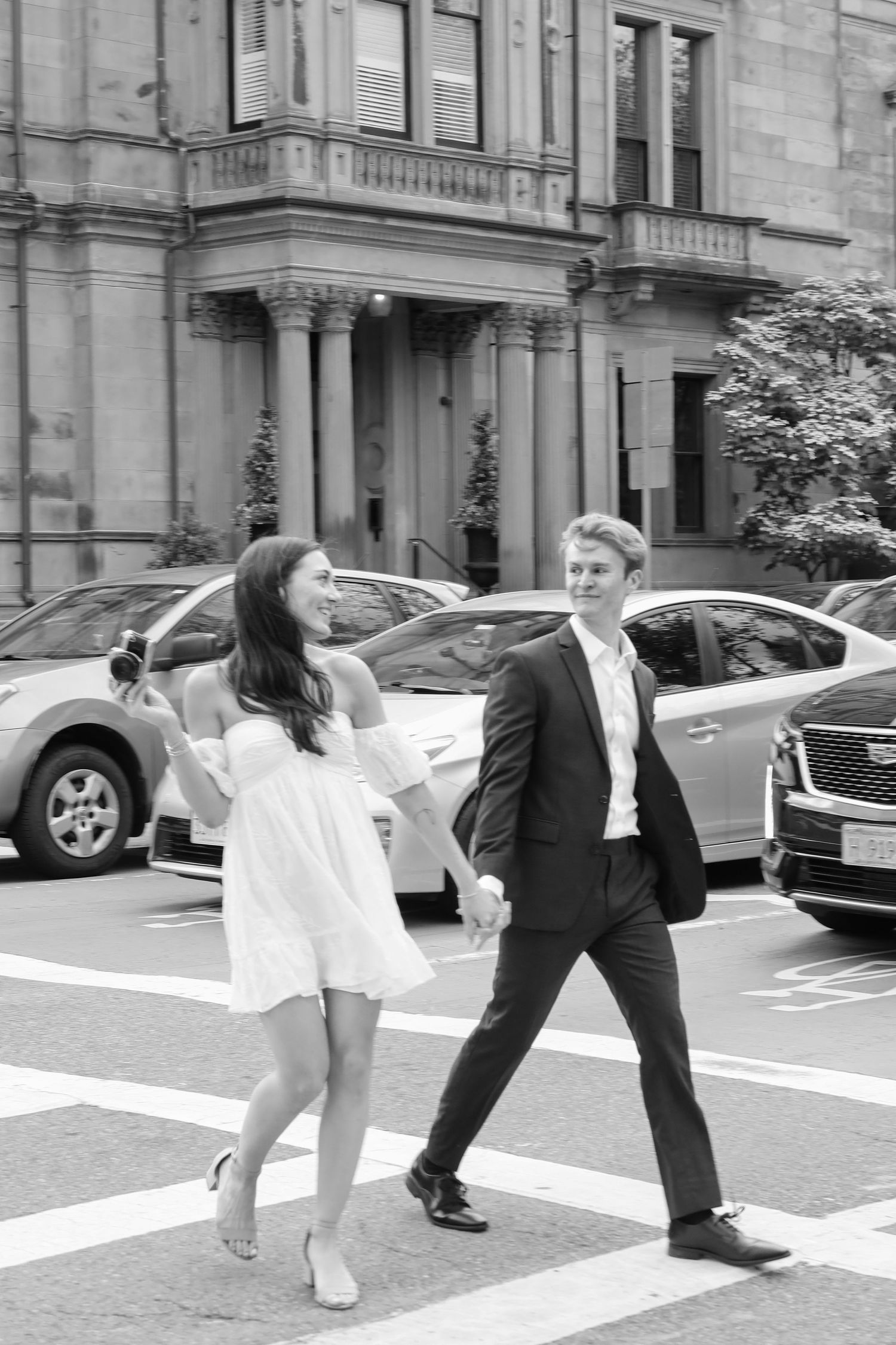 Black and white photo series showing two people crossing an urban street with parked cars.