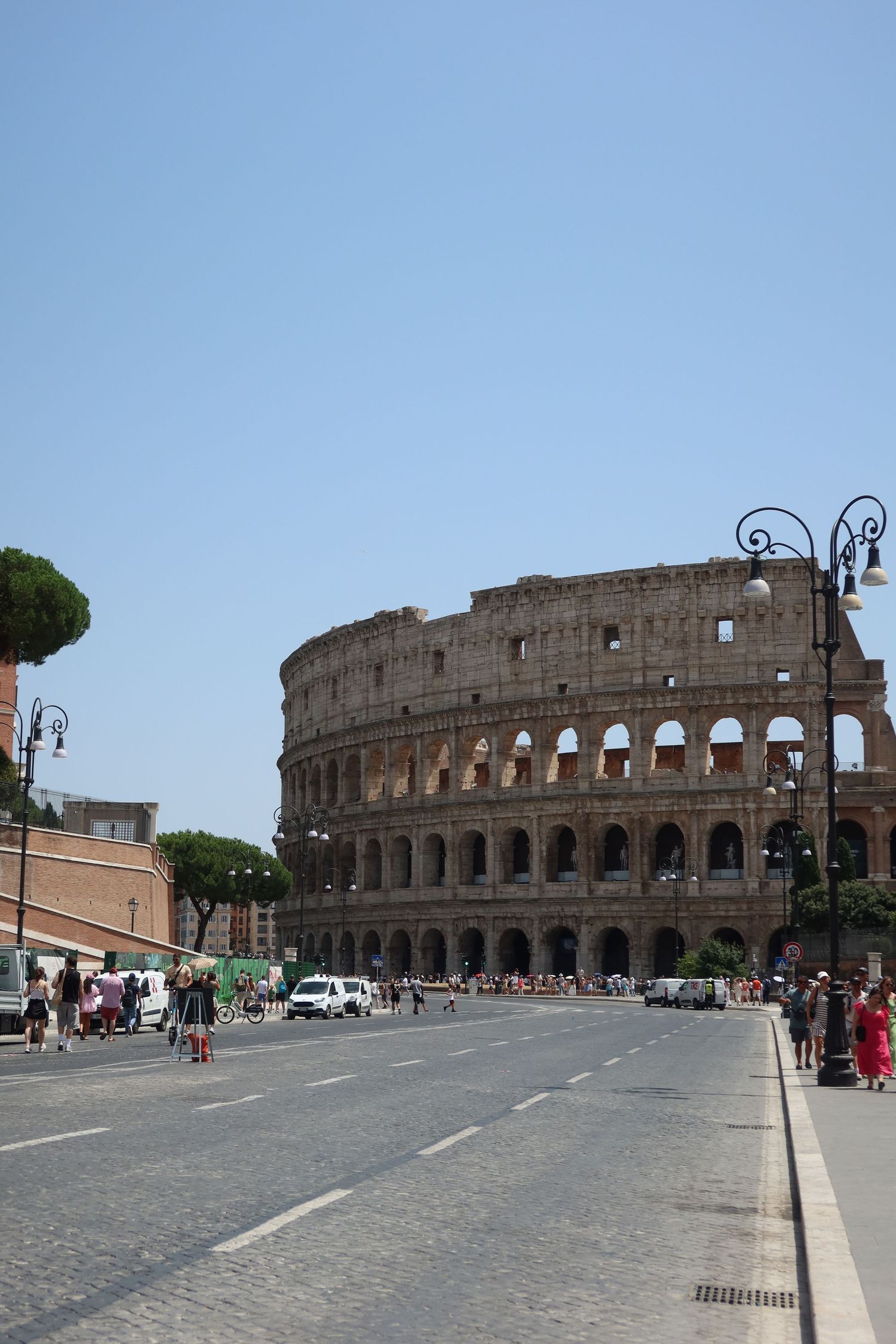 Wide angle view of the Roman Colosseum and surrounding plaza on a sunny day.