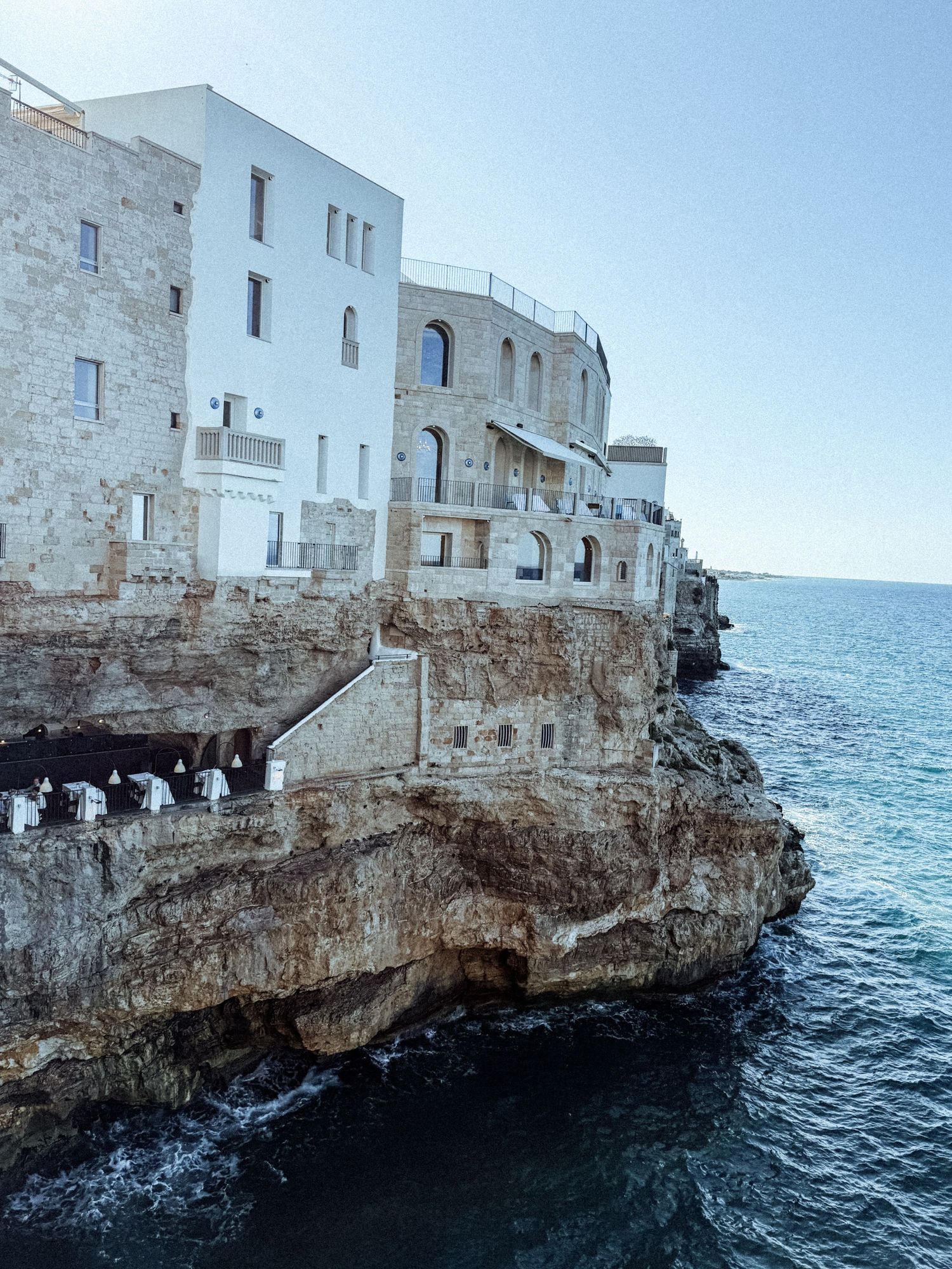 White buildings perched dramatically on limestone cliffs overlooking the deep blue Mediterranean Sea.