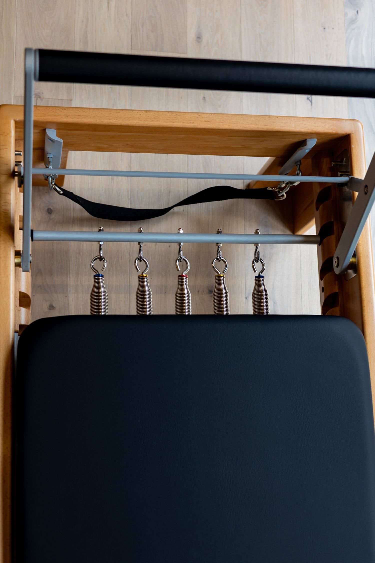 Close-up of black padded equipment with metal hooks mounted on wooden wall in fitness studio.