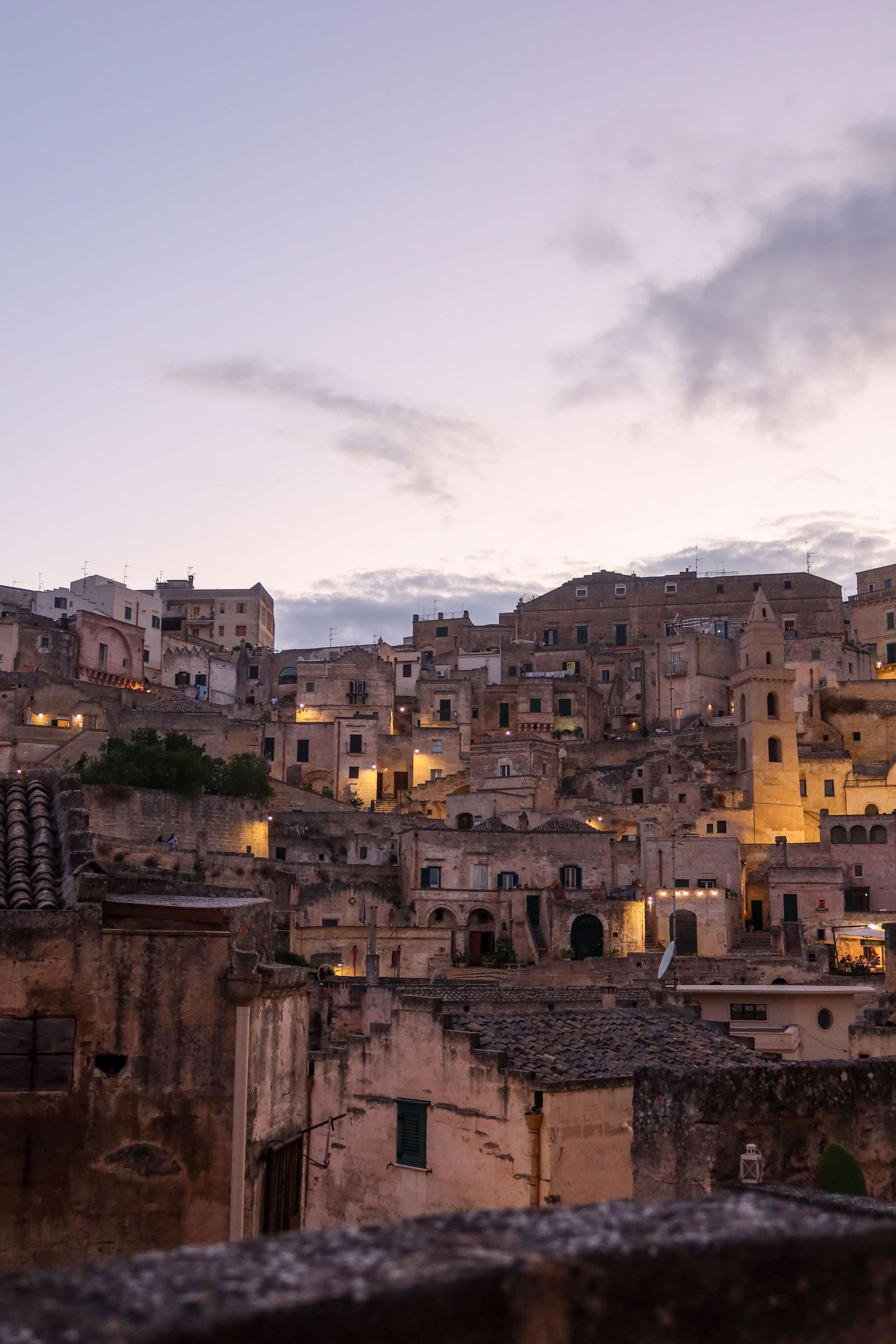 Twilight cityscape of ancient stone buildings with warm lights creating a cozy atmosphere.