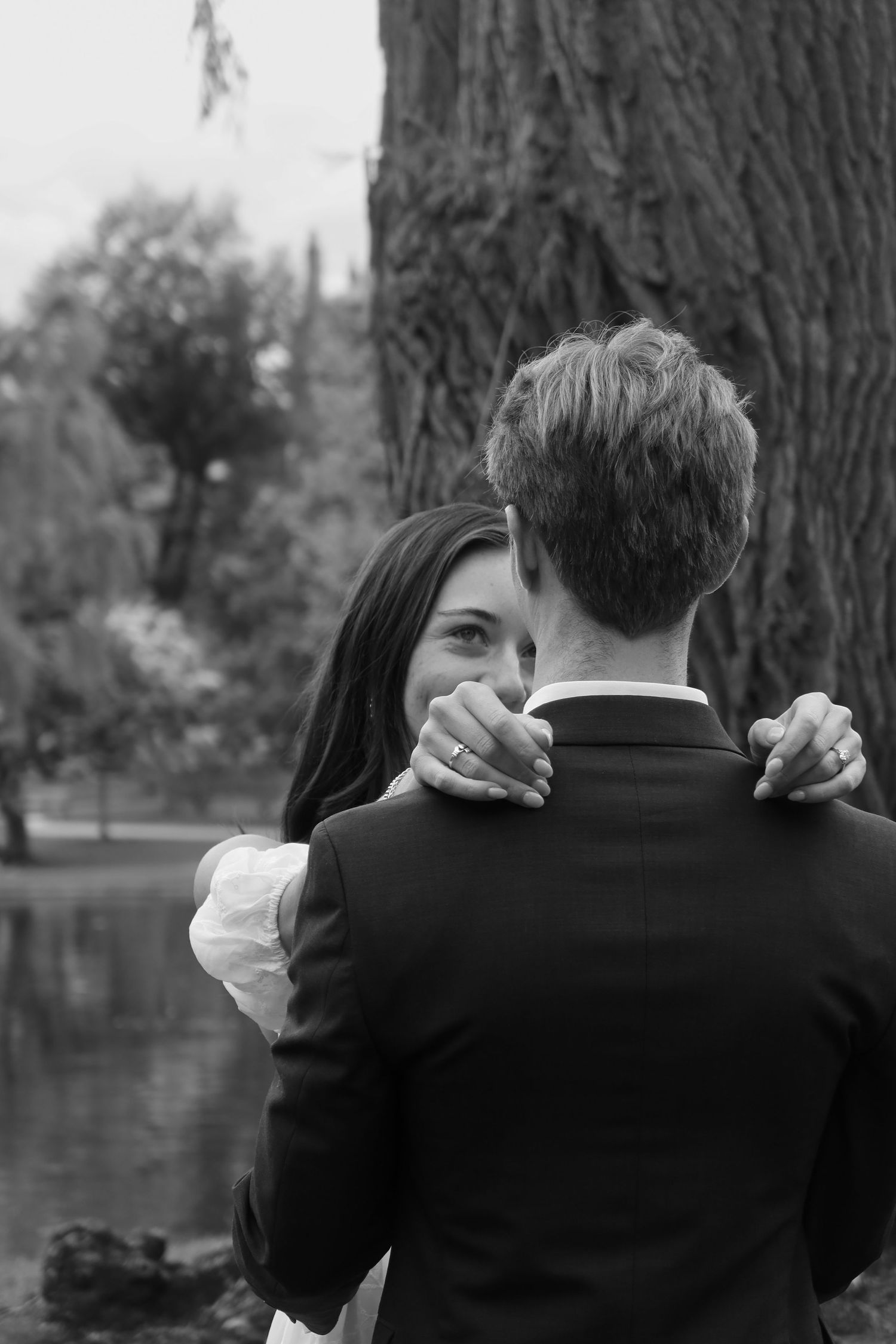 An intimate black and white portrait of two people embracing outdoors.