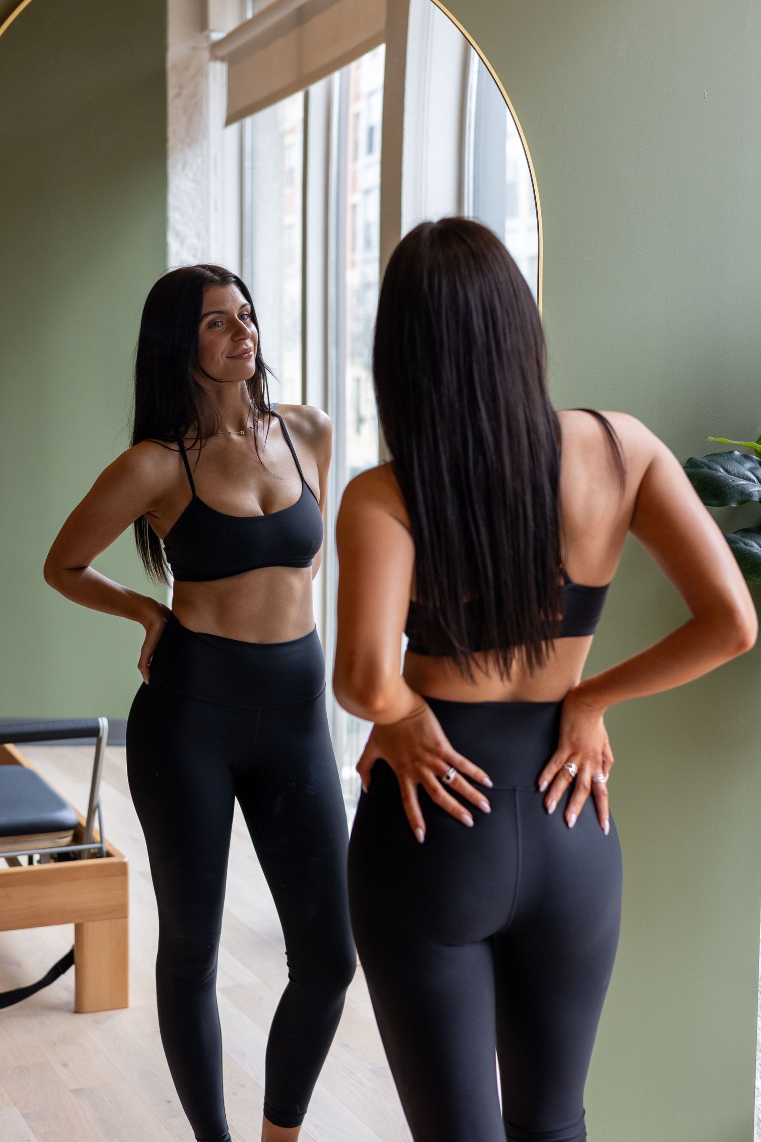 Person in black athletic wear demonstrating different stretching poses against a green wall.