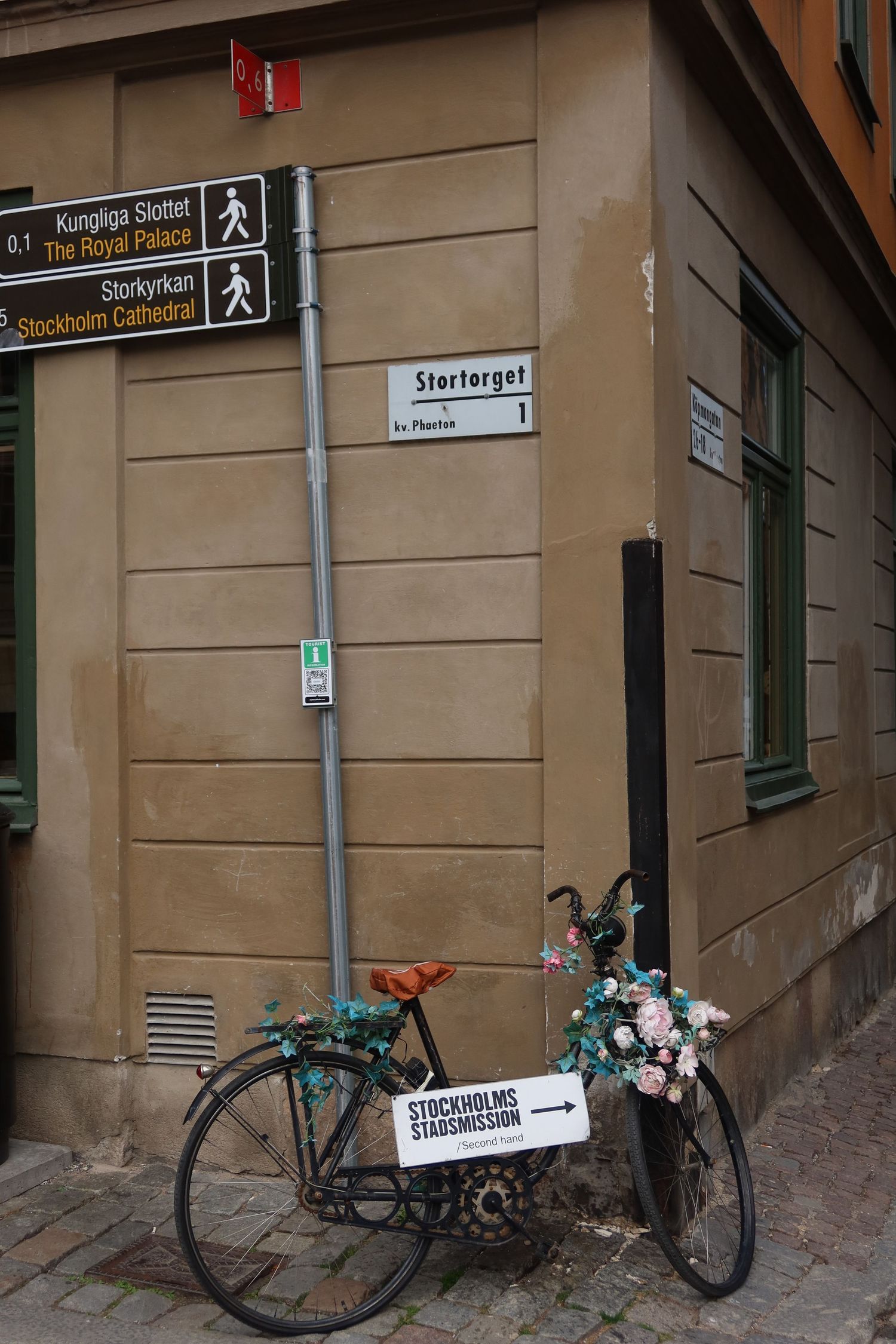 Street corner with directional signs and parked bicycle in Stockholm's historic district.