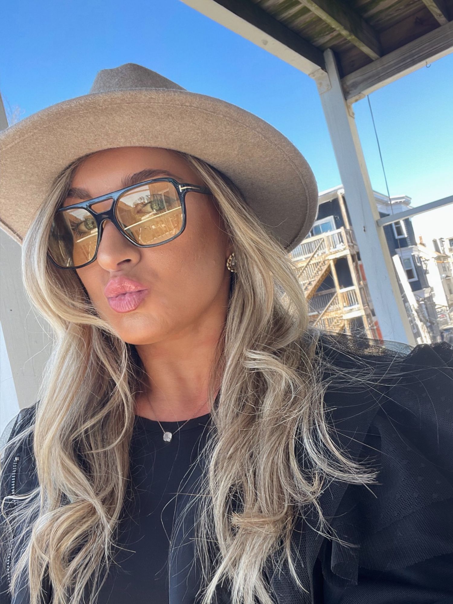 Stylish selfies taken under a covered porch showing sunglasses and a fashionable hat.