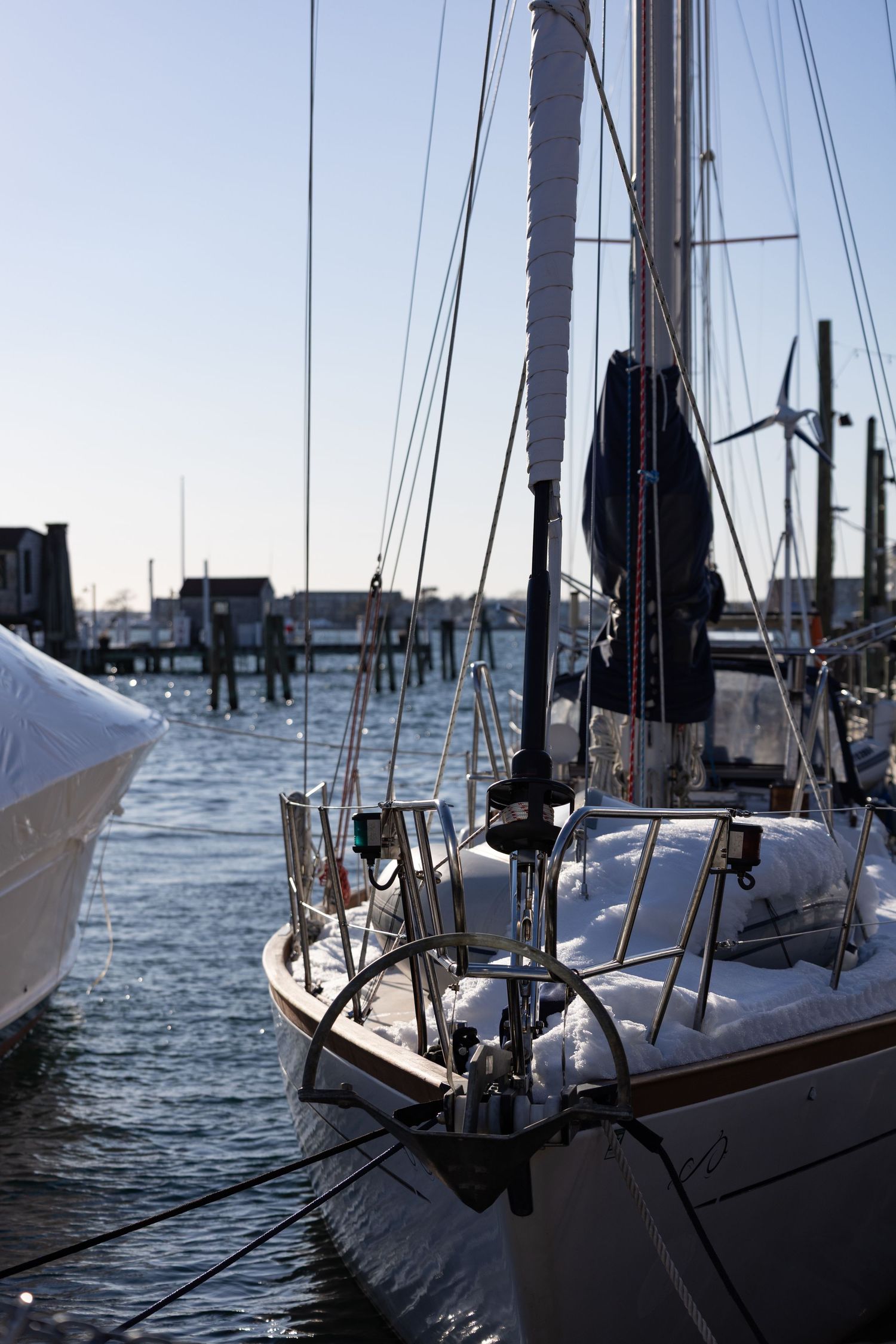 A series of sailboats moored in a harbor at dusk with masts silhouetted against the evening sky.