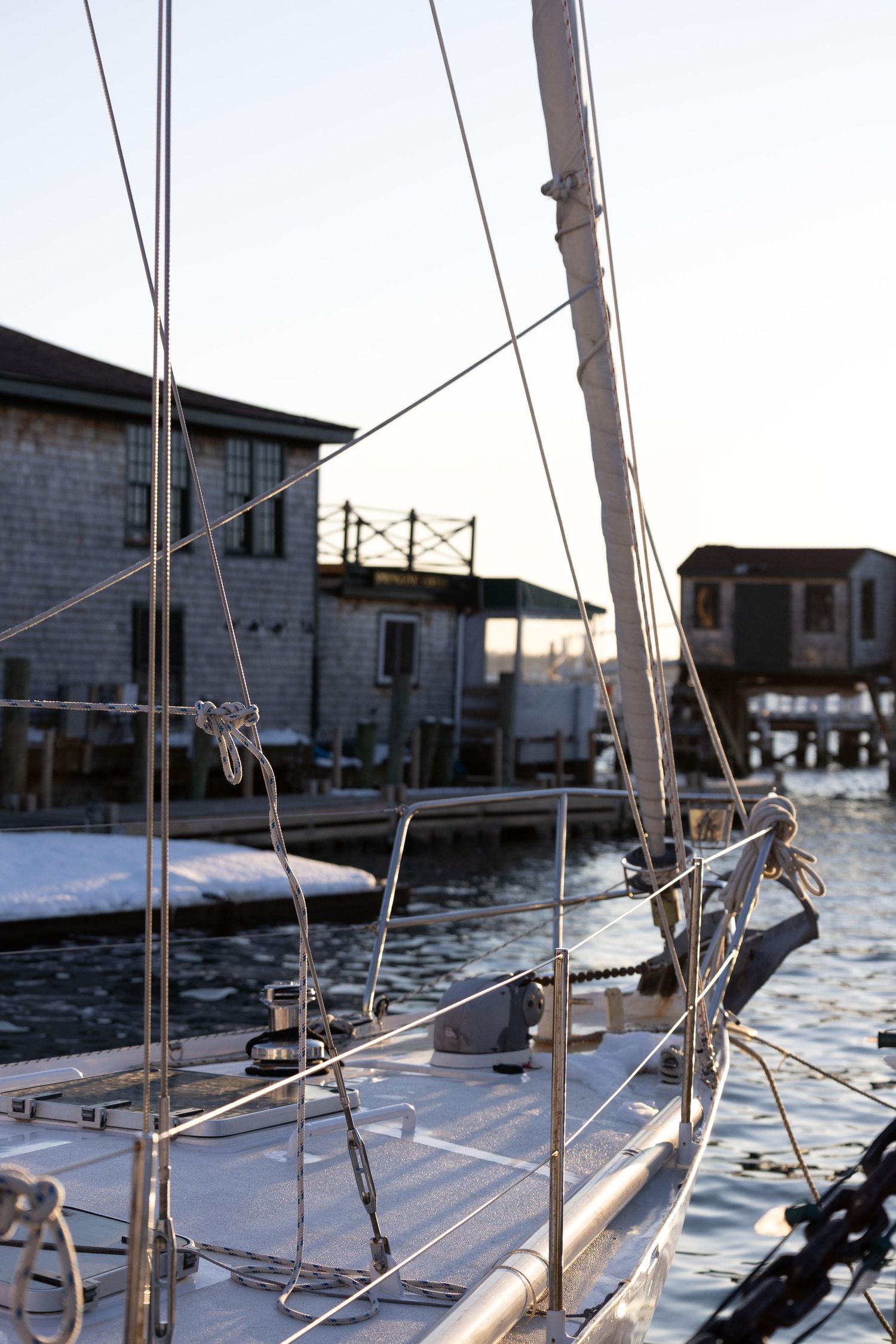 Close-up view of sailboat rigging and masts against a waterfront building on a sunny day.