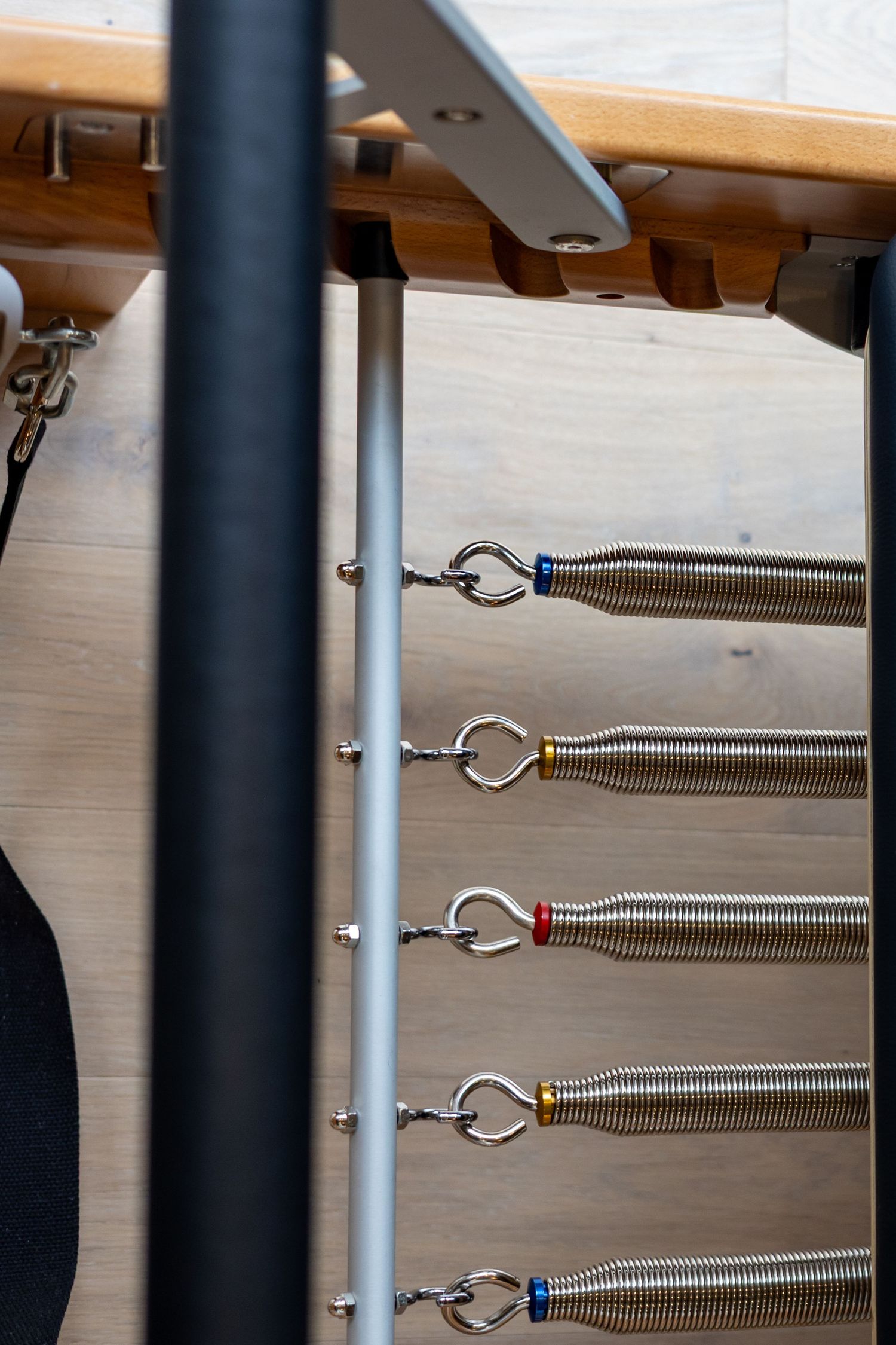 Close-up of metal springs and attachments on Pilates reformer equipment.