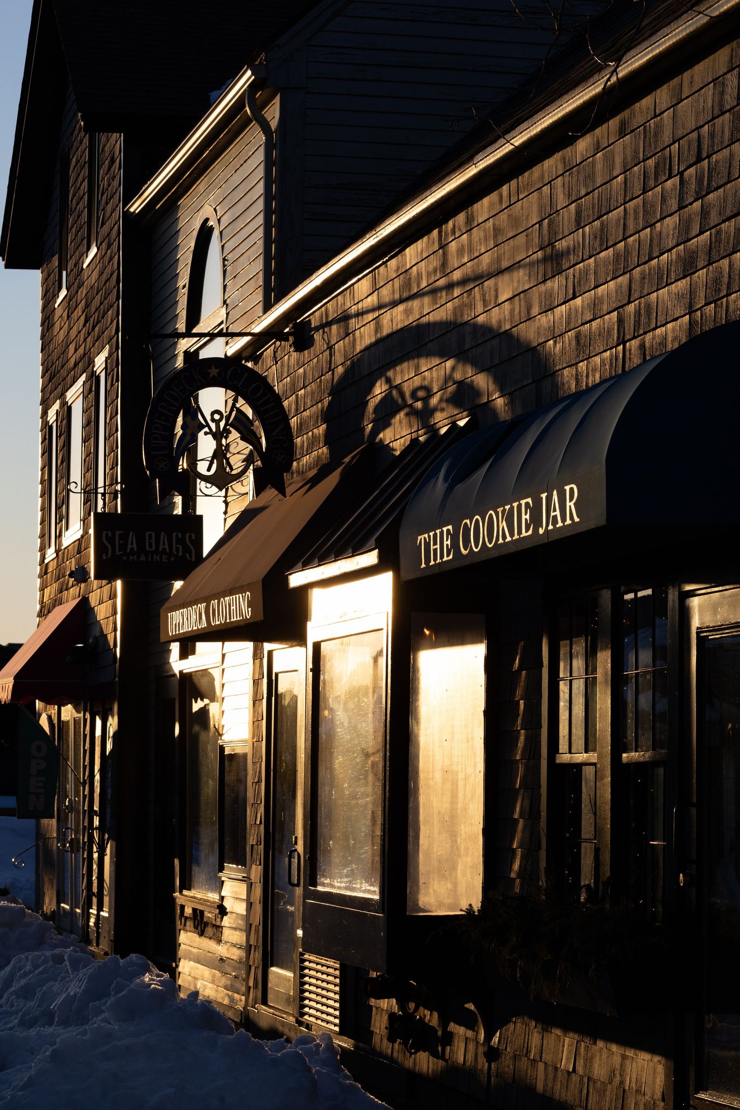Exterior storefront view of The Cookie Jar shop at dusk with warm lighting and brick building facade.