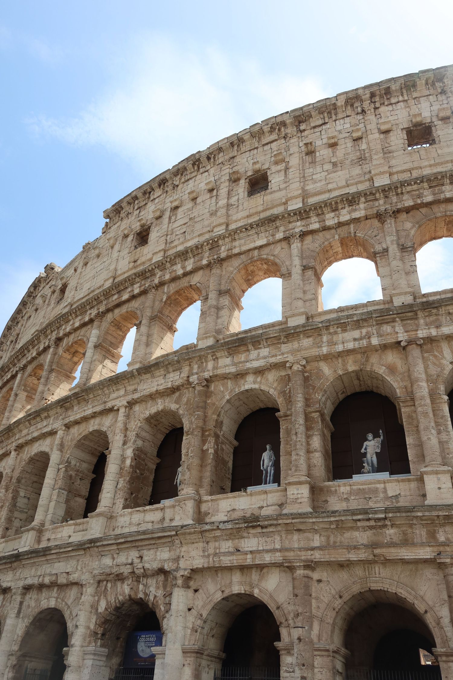 Ancient stone arches of the Roman Colosseum showcase classical architecture against a blue sky.