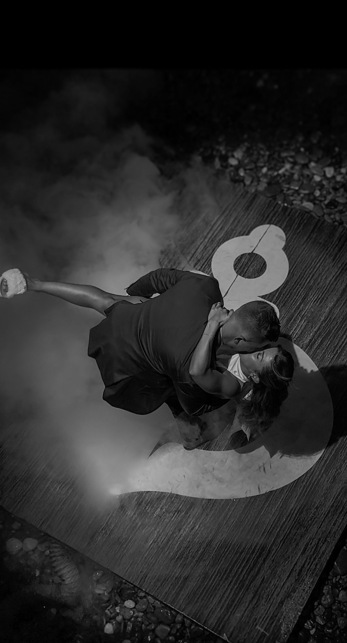 Dancers moving gracefully across a dimly lit stage with atmospheric smoke effects.