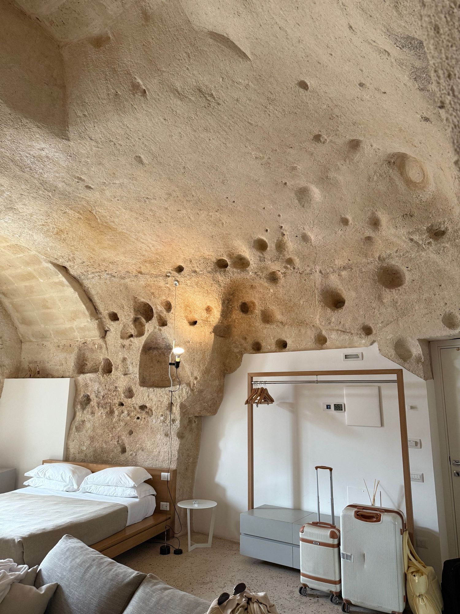 A cave hotel room with textured stone walls and modern white furnishings.