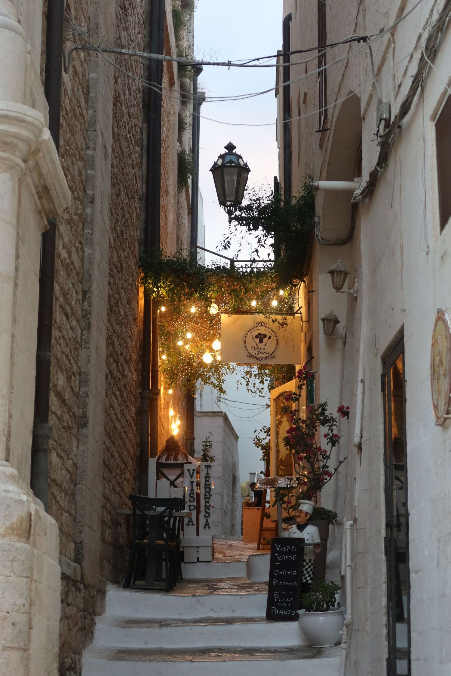 Charming narrow alley with white walls and hanging lights in a Mediterranean town.