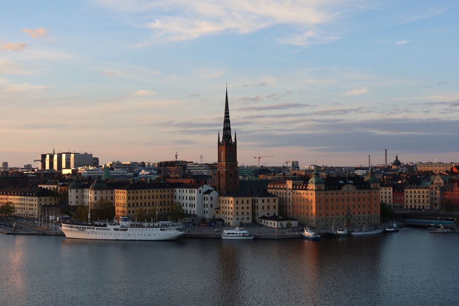 Panoramic waterfront view of Stockholm's skyline with boats and historic buildings at dusk.