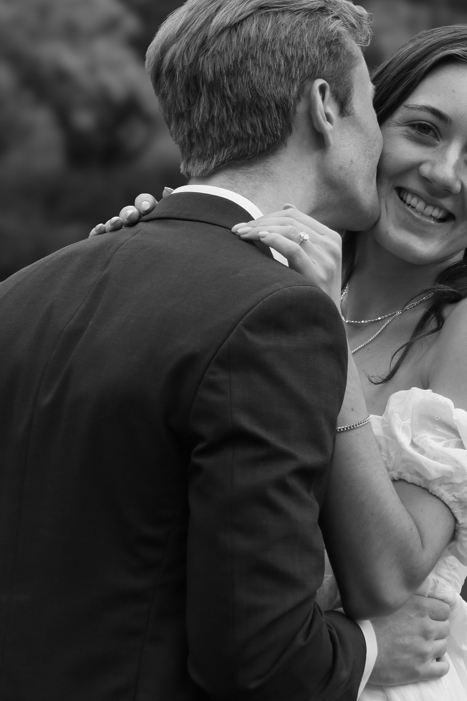 black and white engagement photo of man kissing womans cheek