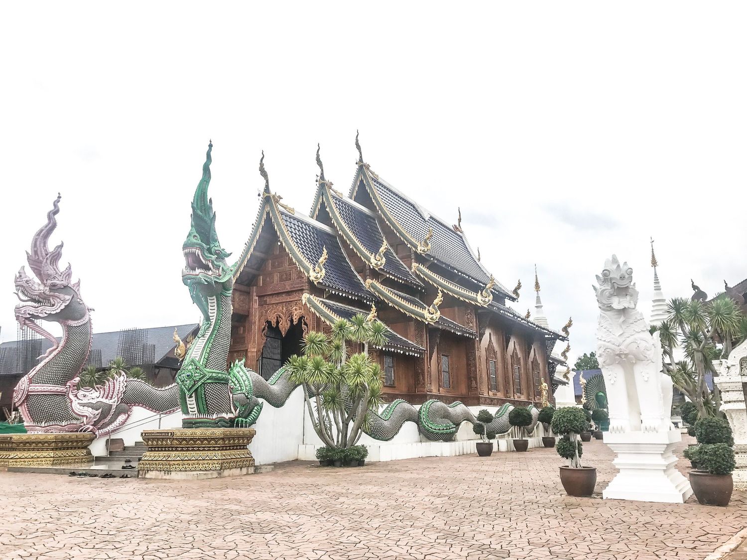 Traditional Thai temple architecture with ornate roofs and white statues.
