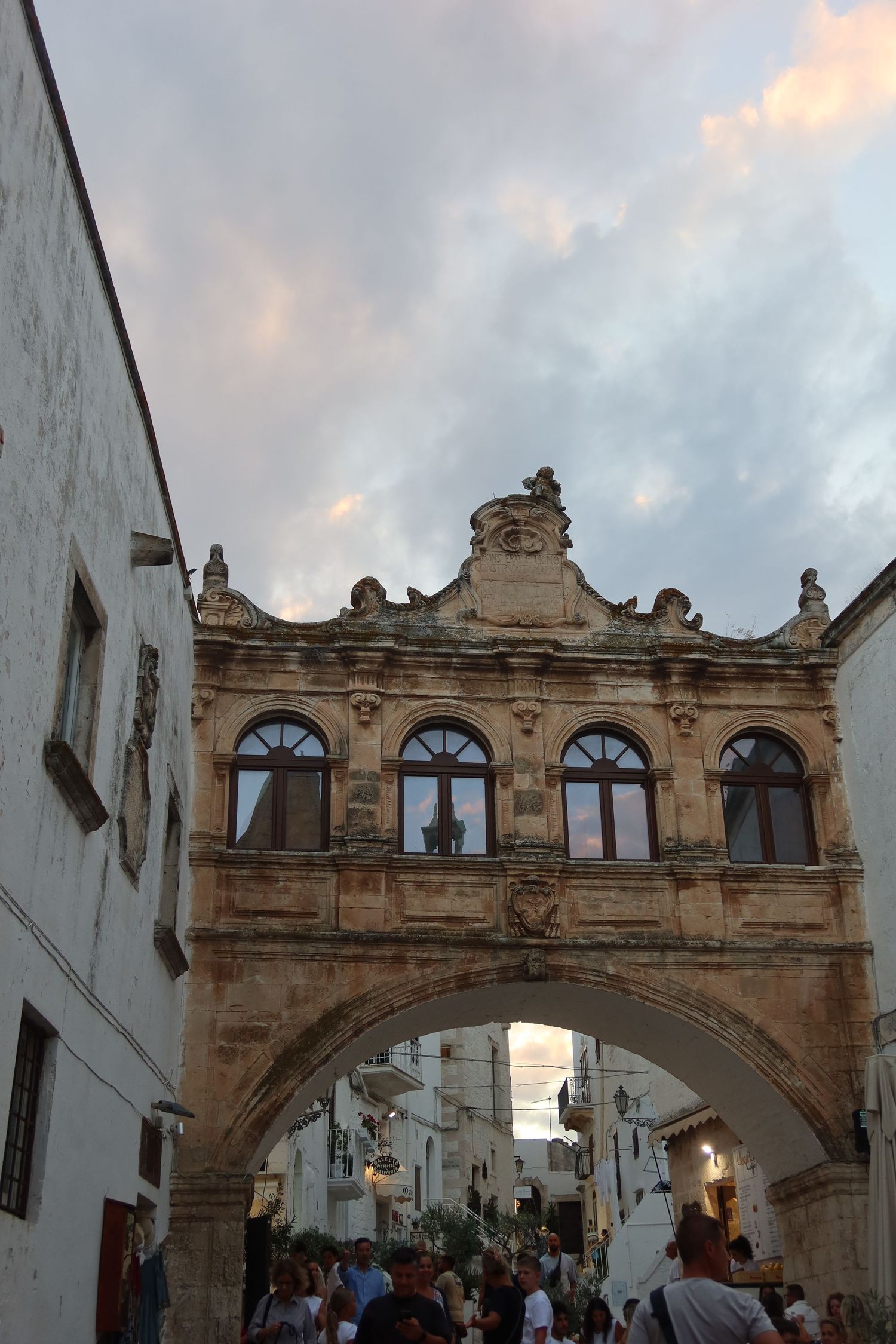 Historic stone archway bridge connecting buildings in an Italian town center.